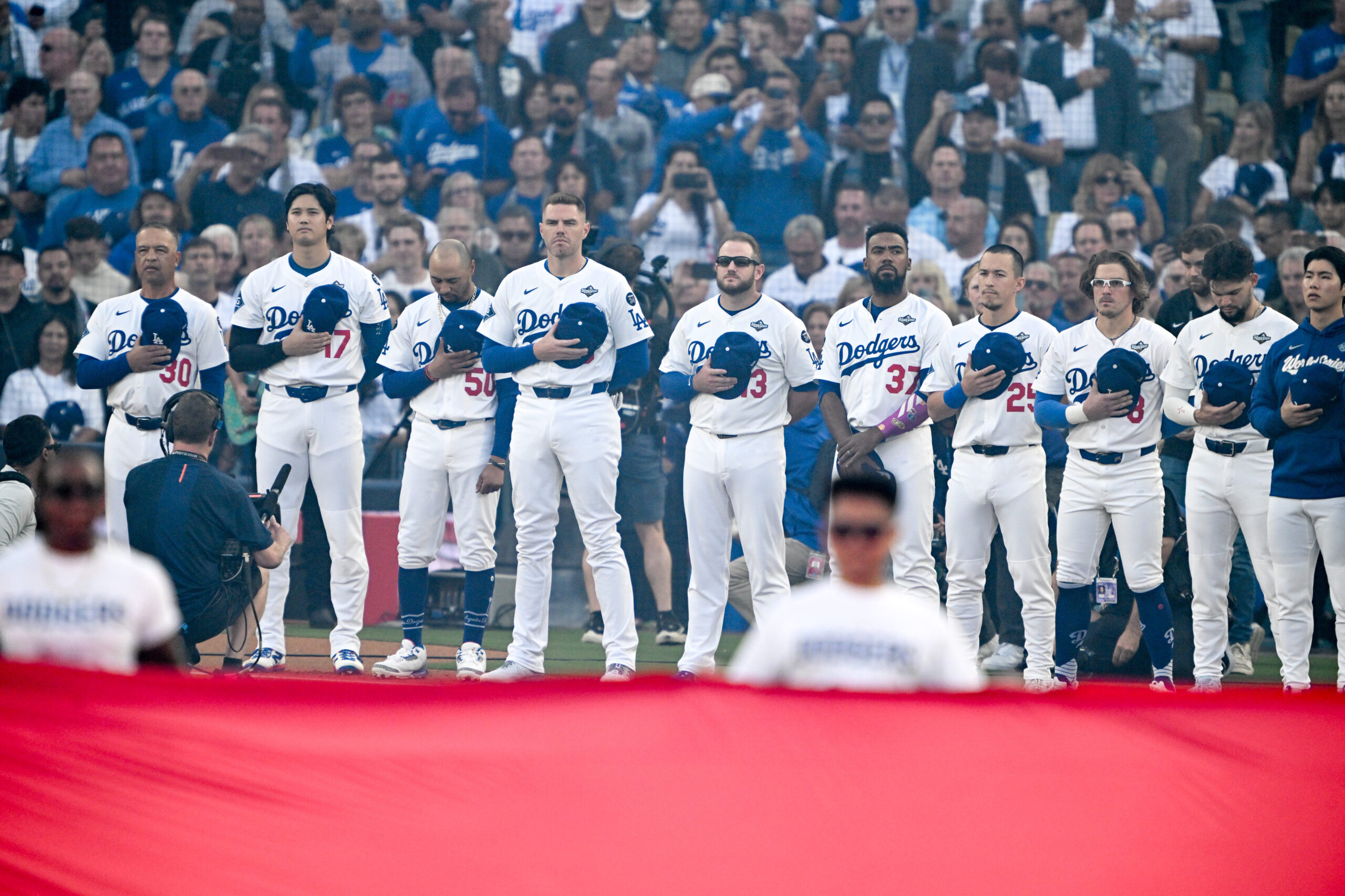 Dodgers players and coaches stand for the National Anthem before...