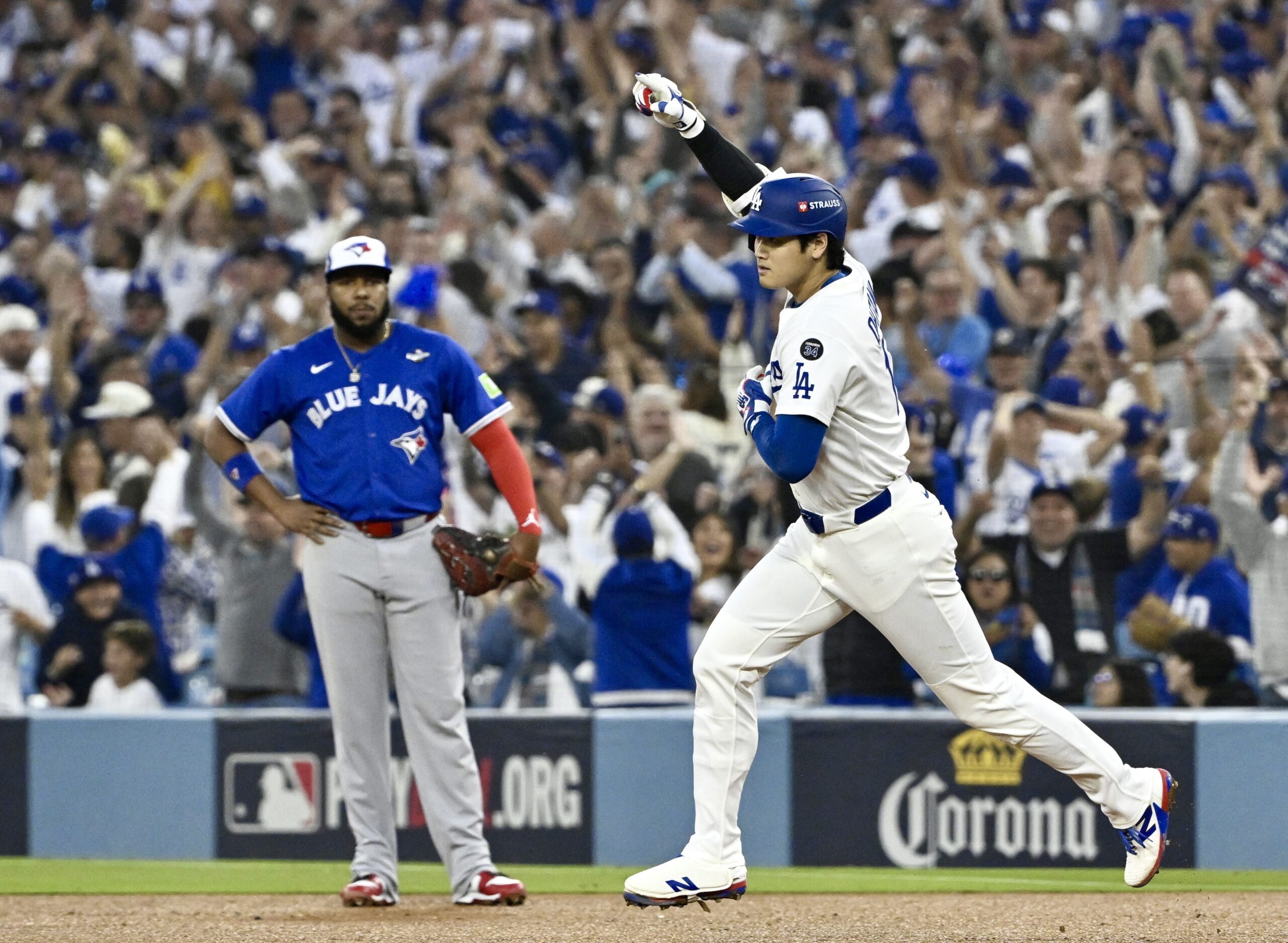 Dodgers star Shohei Ohtani, right, runs the bases in front...