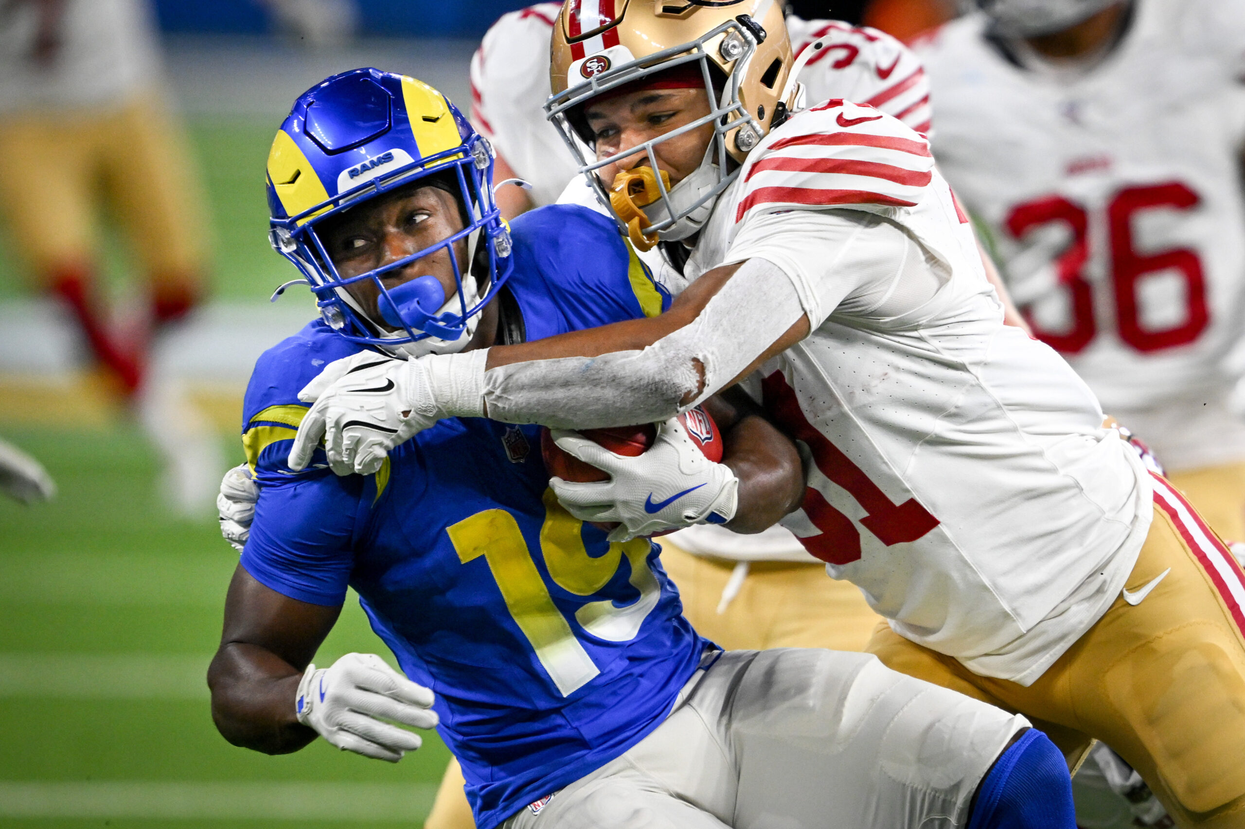 Rams Xavier Smith (19) is pulled down by 49ers Isaac...