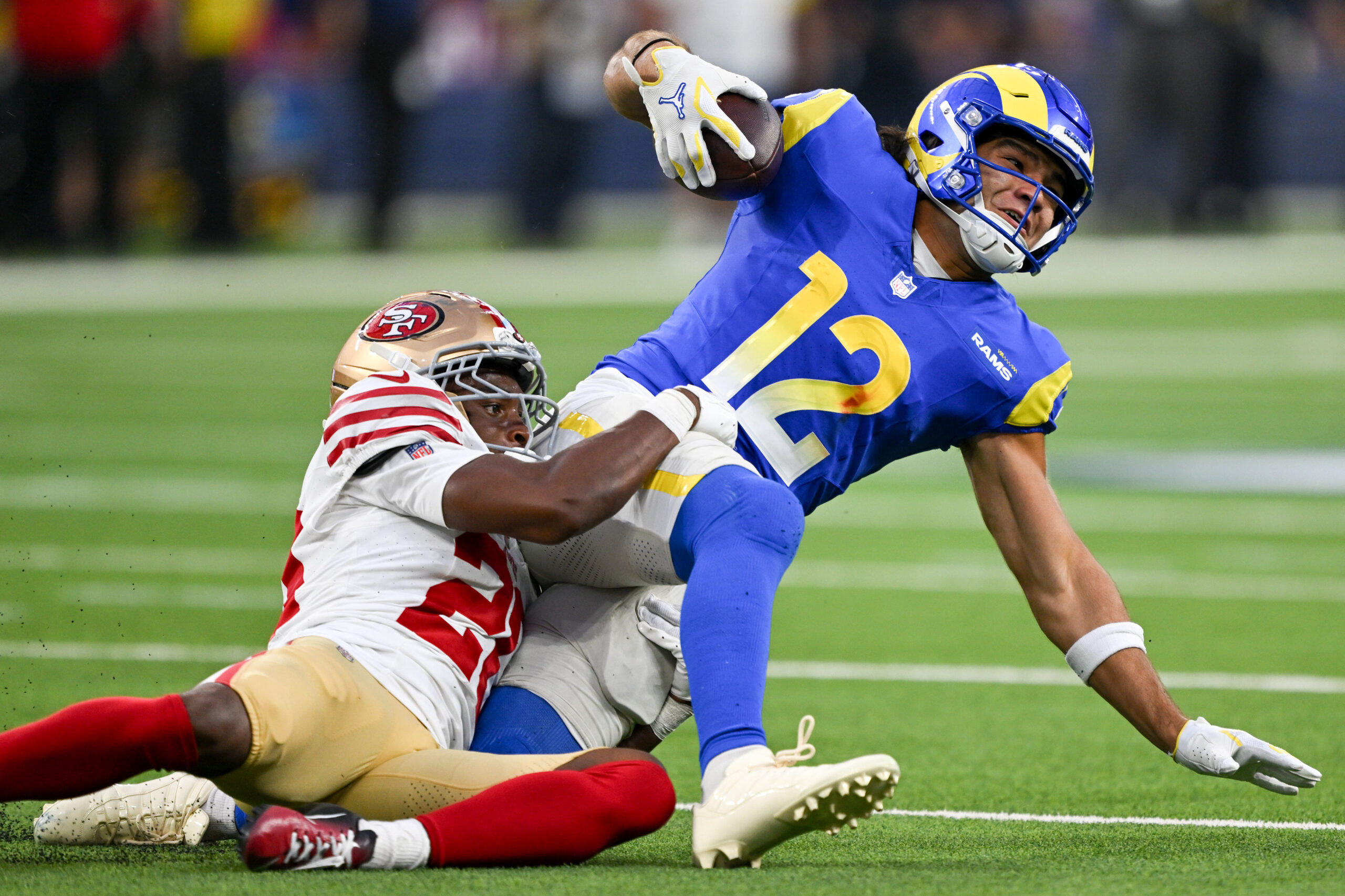 Rams wide receiver Puka Nacua, right, tries for extra yardage...