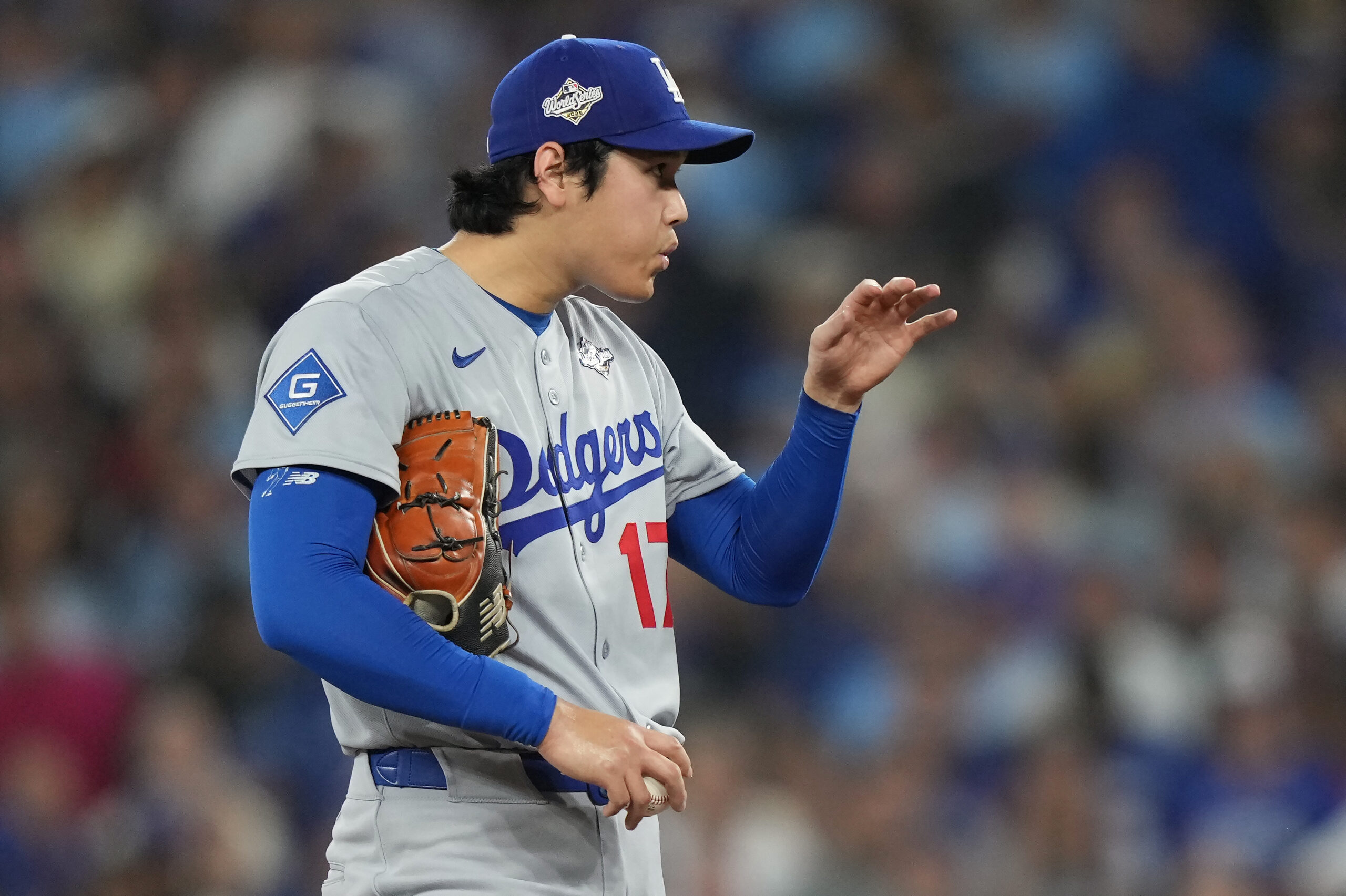 Dodgers starting pitcher Shohei Ohtani blows on his fingers during...
