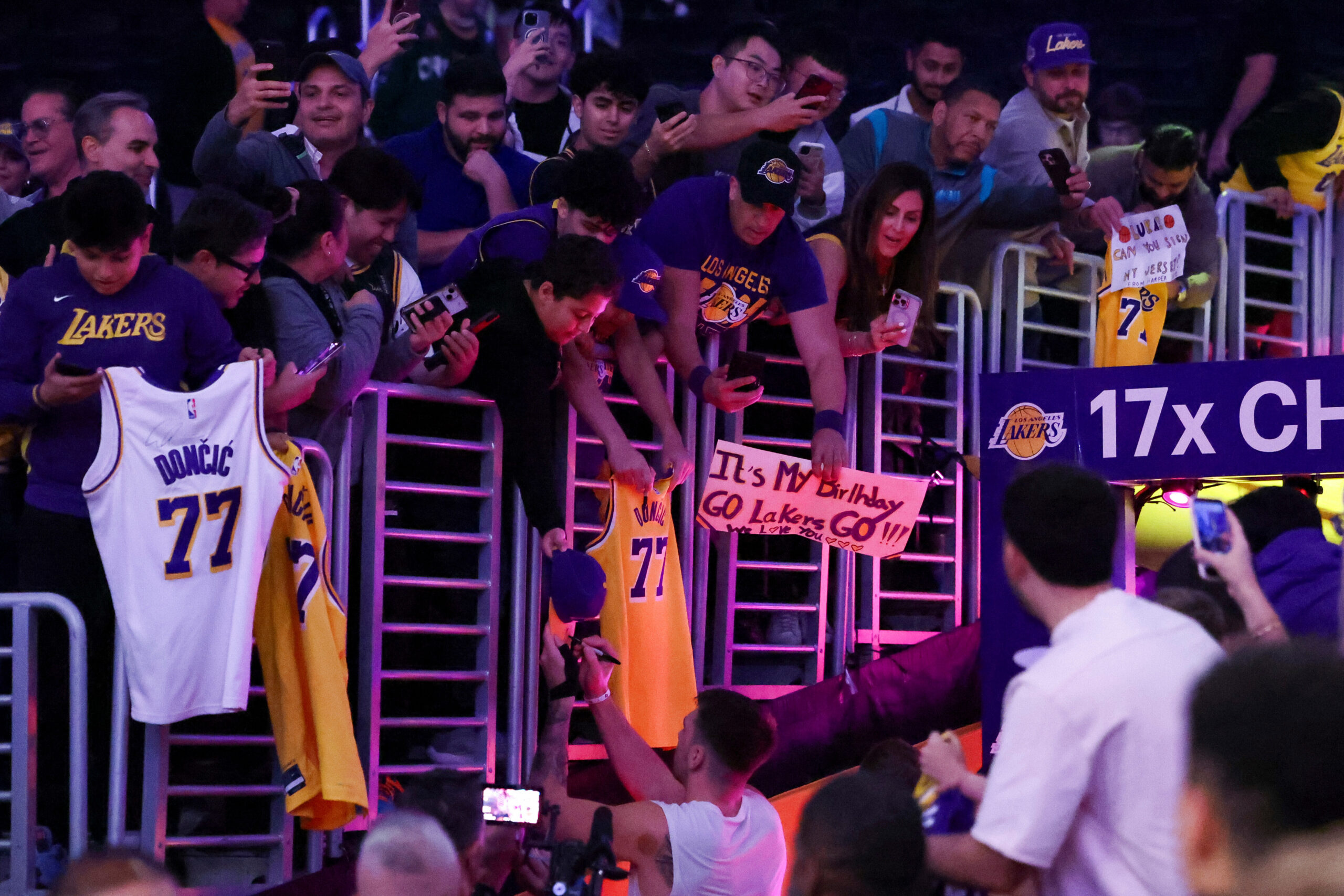 Lakers guard Luka Doncic, centter bottom, gives autographs to fans...