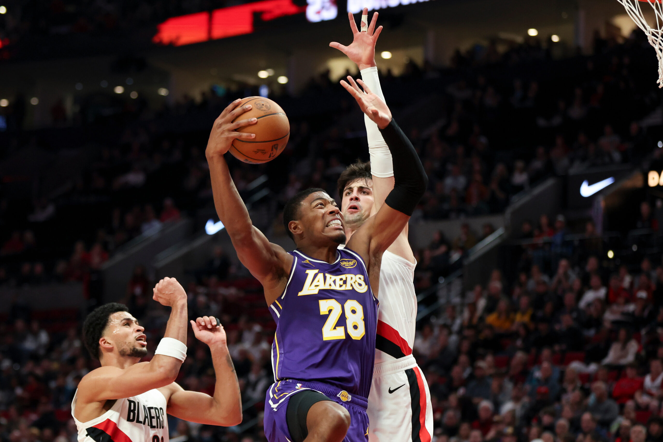 Lakers forward Rui Hachimura, center, drives to the basket between...