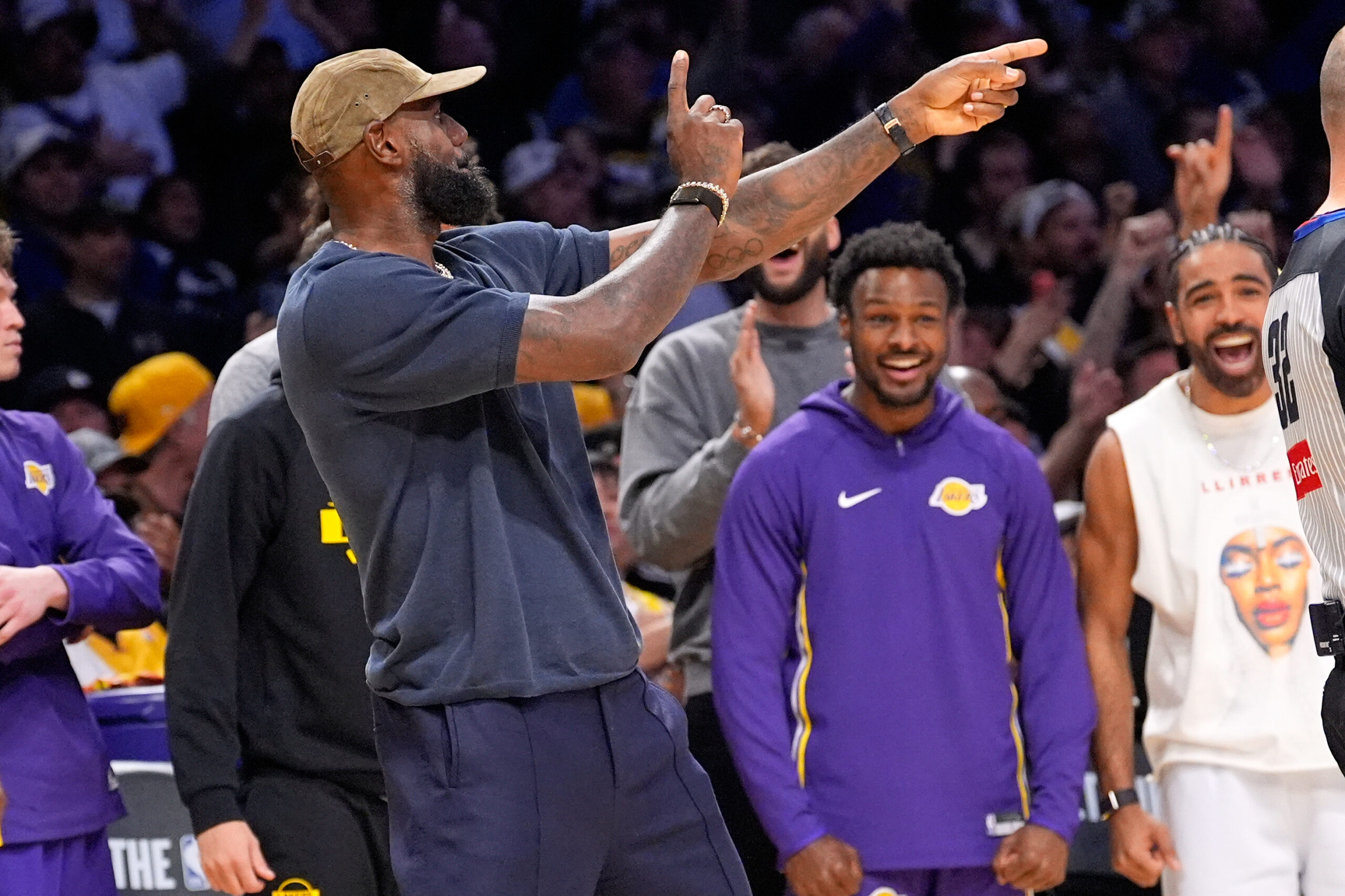 Injured Lakers star LeBron James, left, and Bronny James, center,...