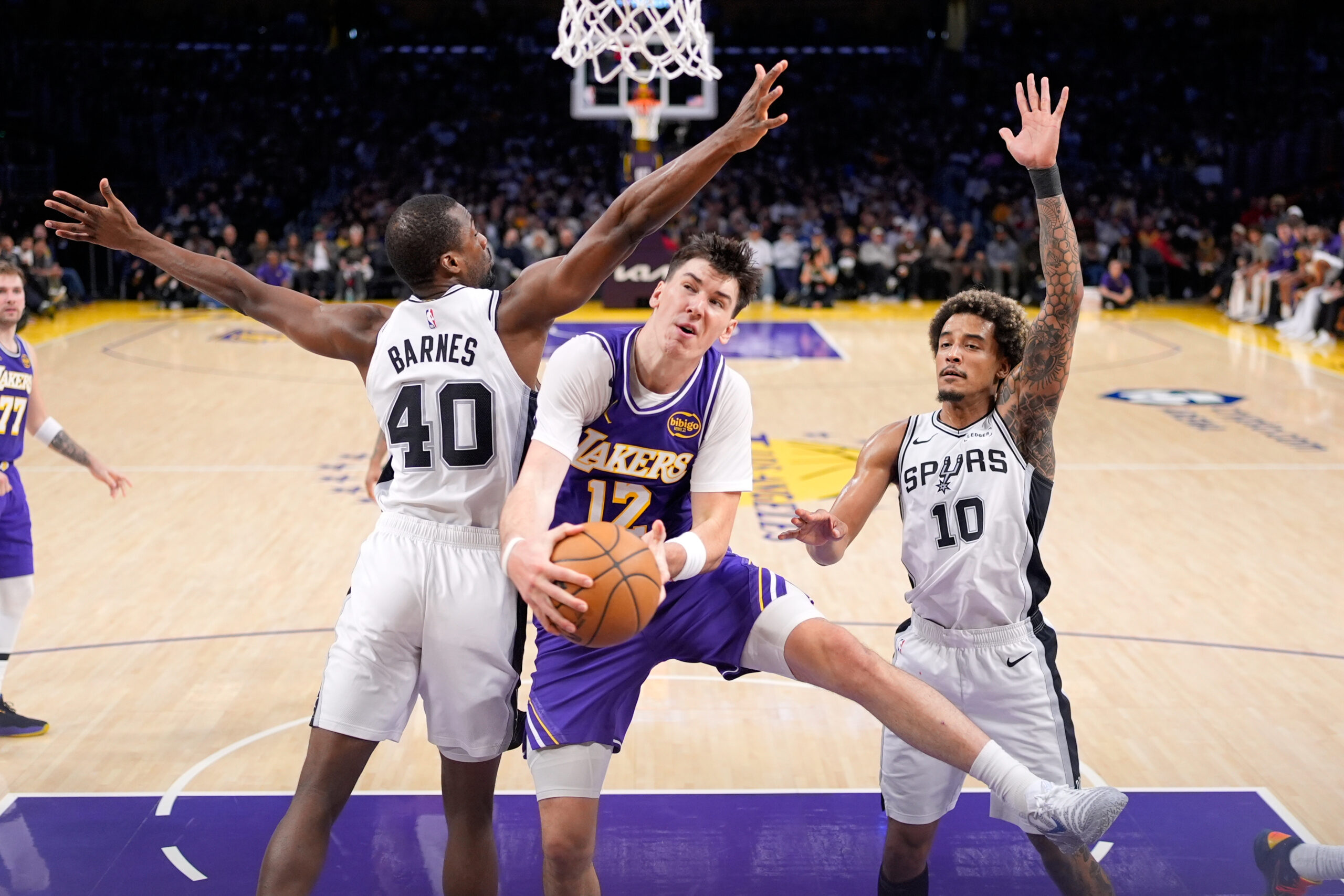 Lakers forward Jake LaRavia, center, shoots as San Antonio Spurs...