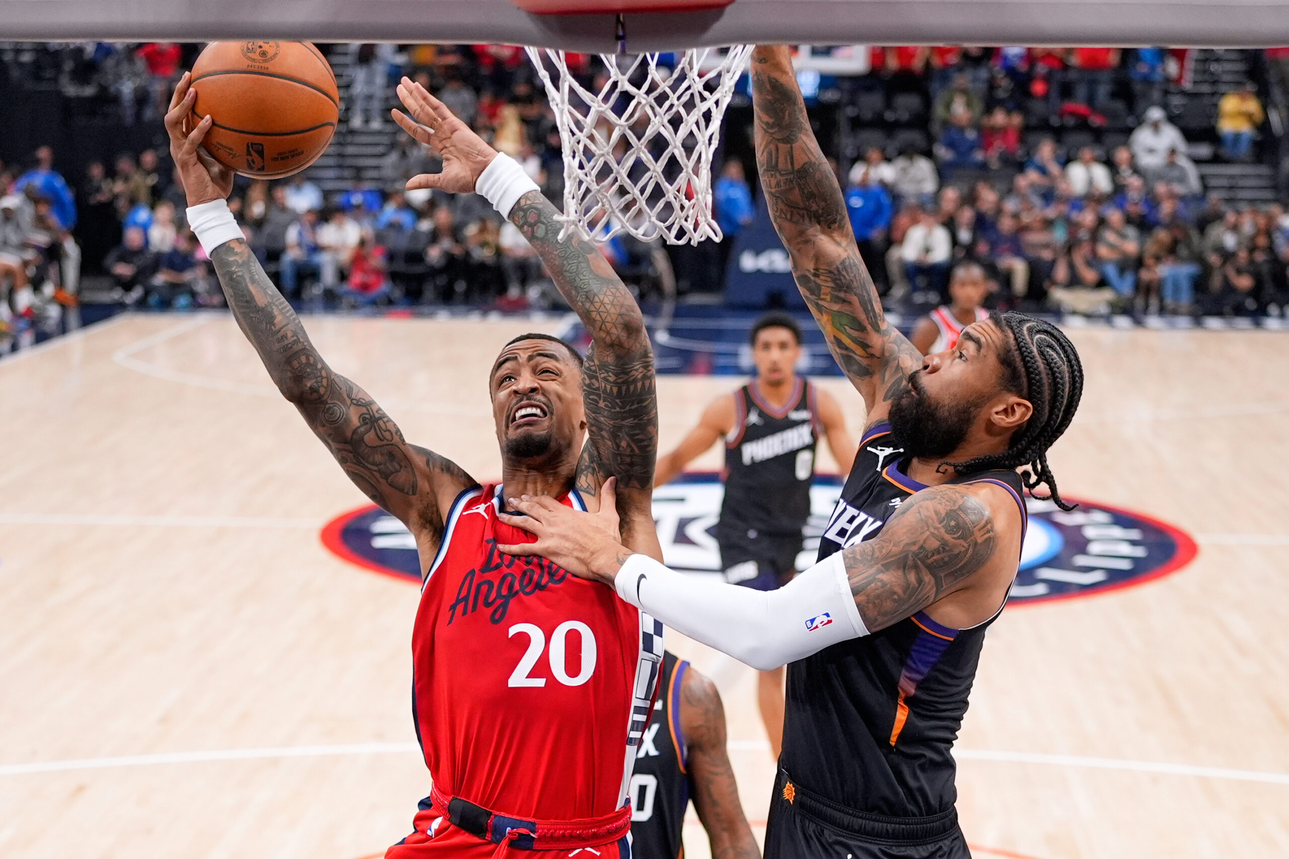 Clippers forward John Collins, left, shoots as Phoenix Suns center...