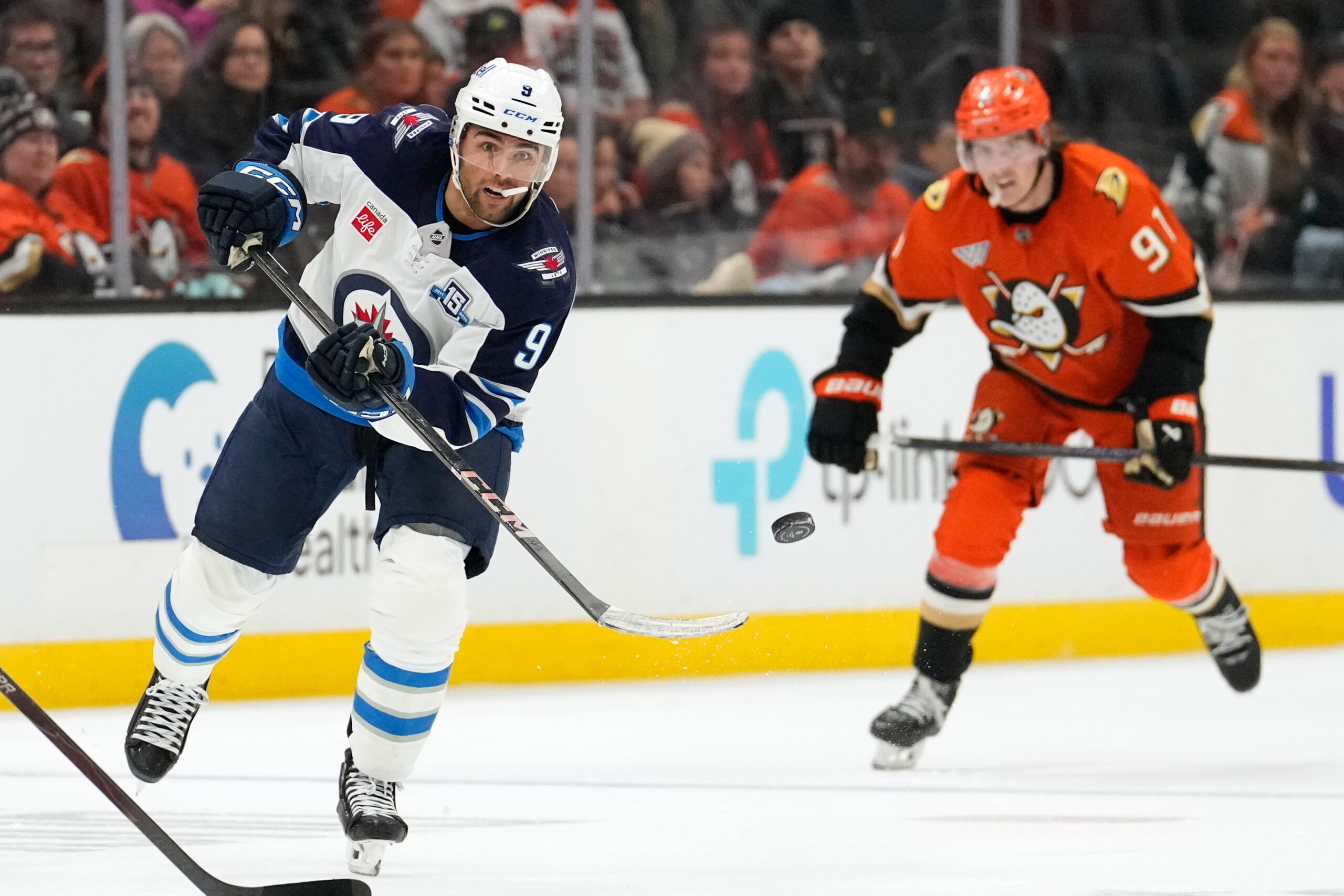 Winnipeg Jets left wing Alex Iafallo, left, passes the puck...
