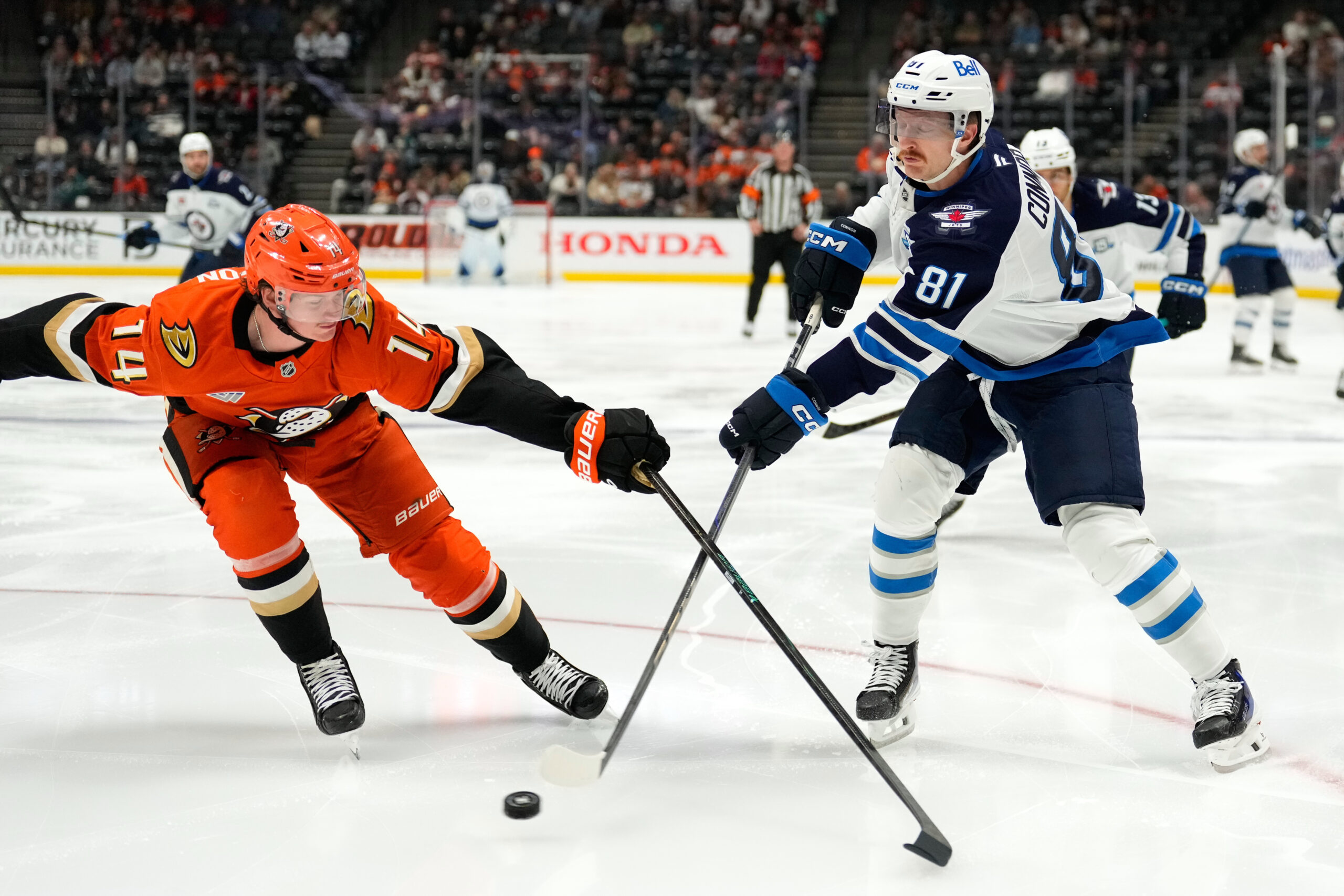 Winnipeg Jets left wing Kyle Connor, right, passes the puck...