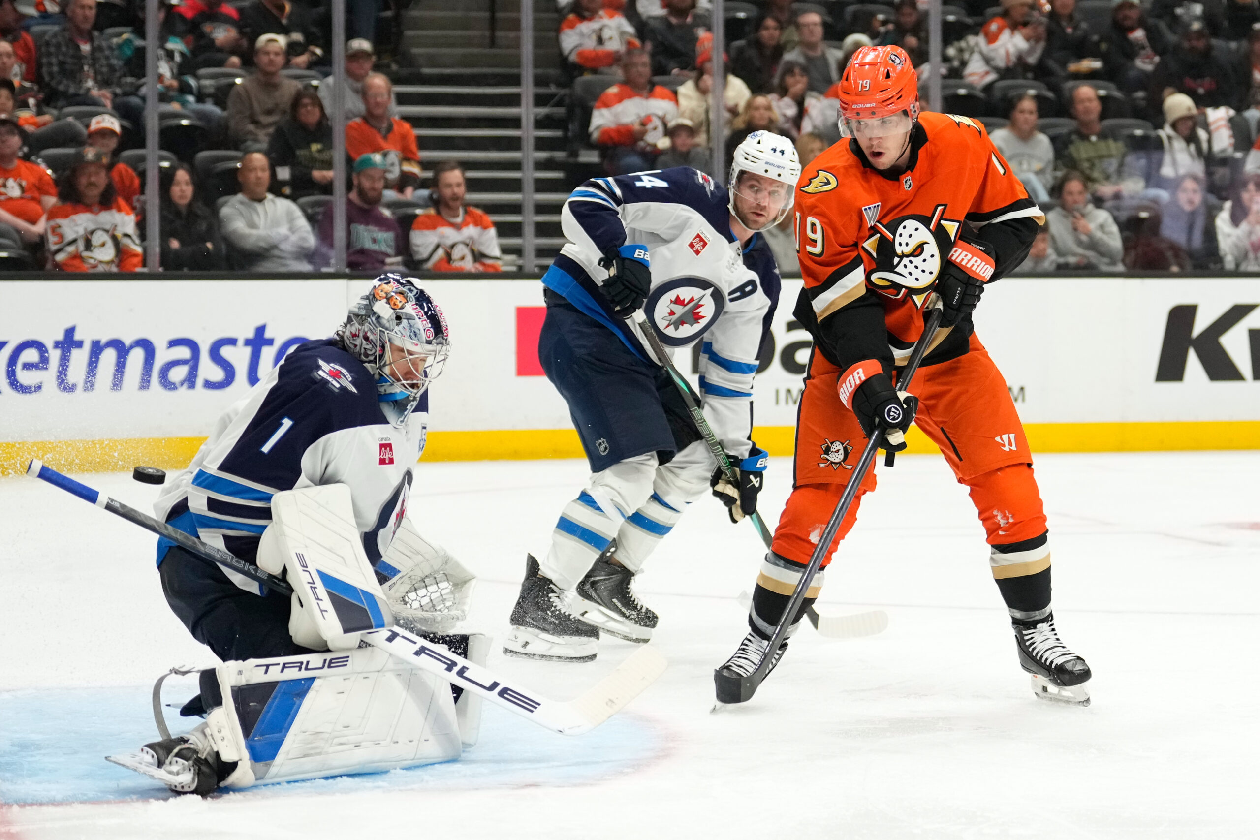 Winnipeg Jets goaltender Eric Comrie, left, is cored on Ducks...