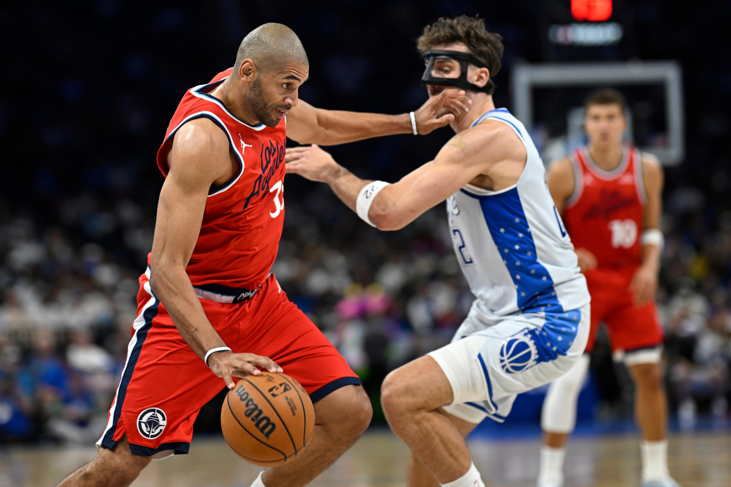 Clippers forward Nicolas Batum, left, is defended by Orlando Magic...