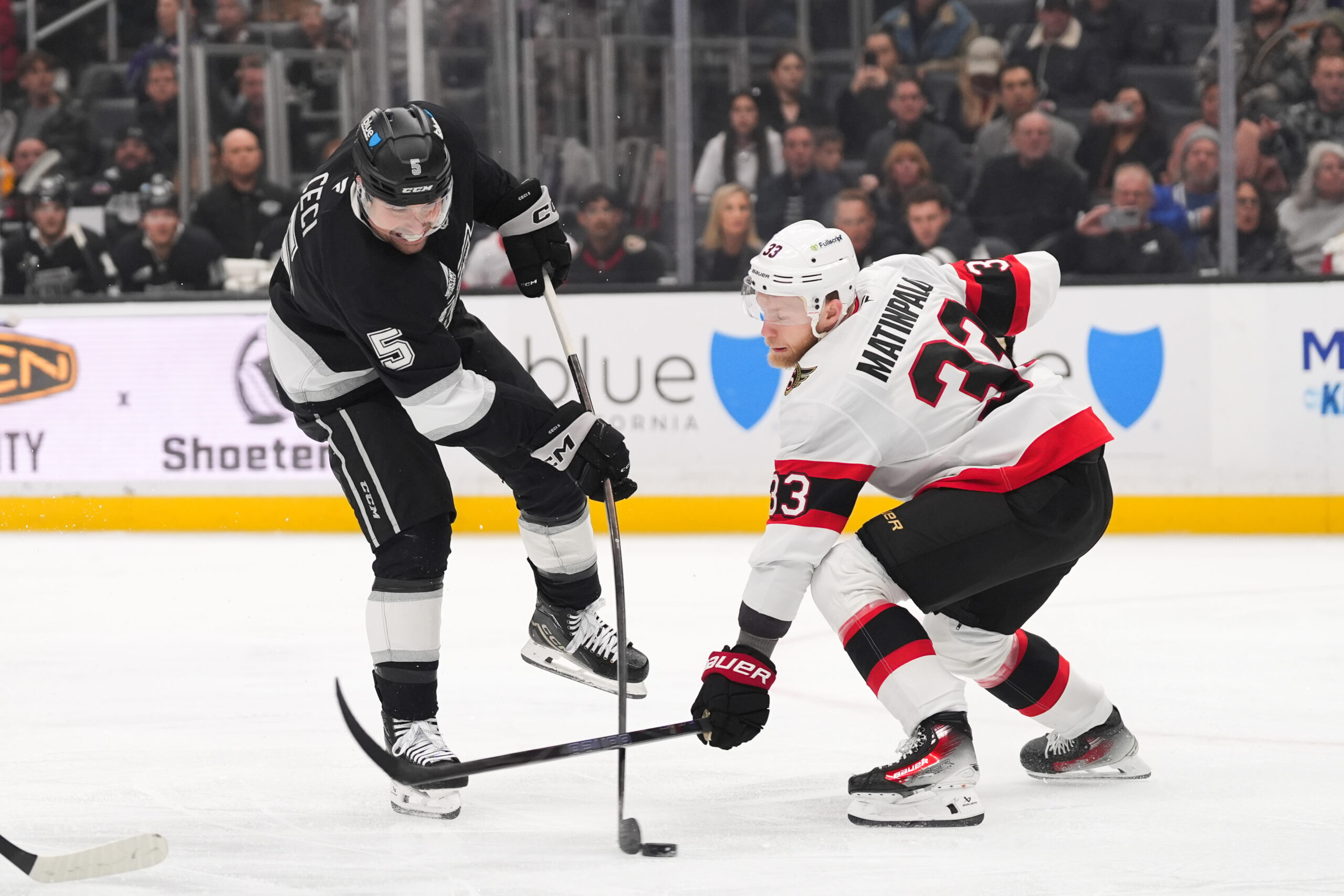 Kings defenseman Cody Ceci, left, shoots the puck as Ottawa...