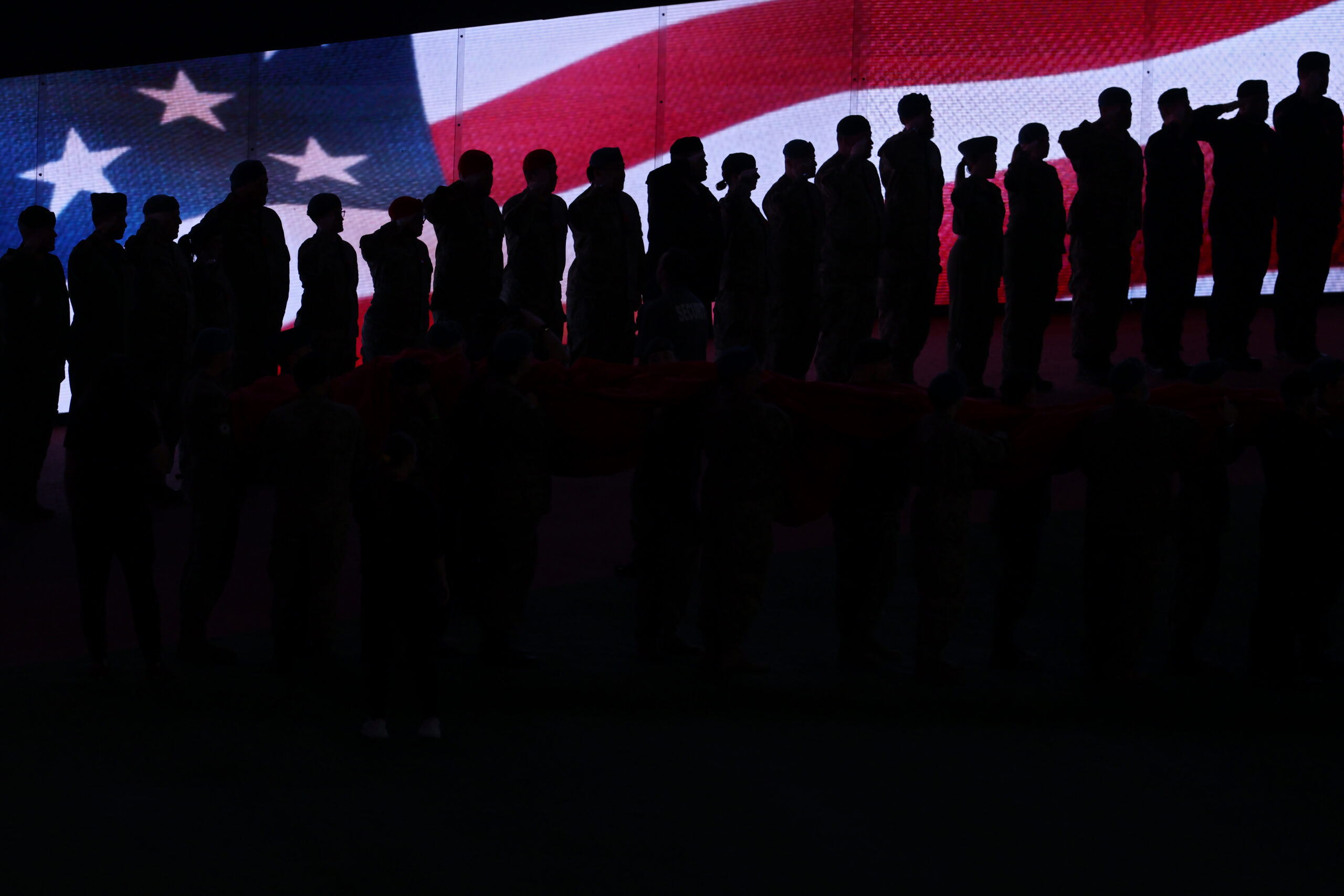 Members of the military salute in front of the American...