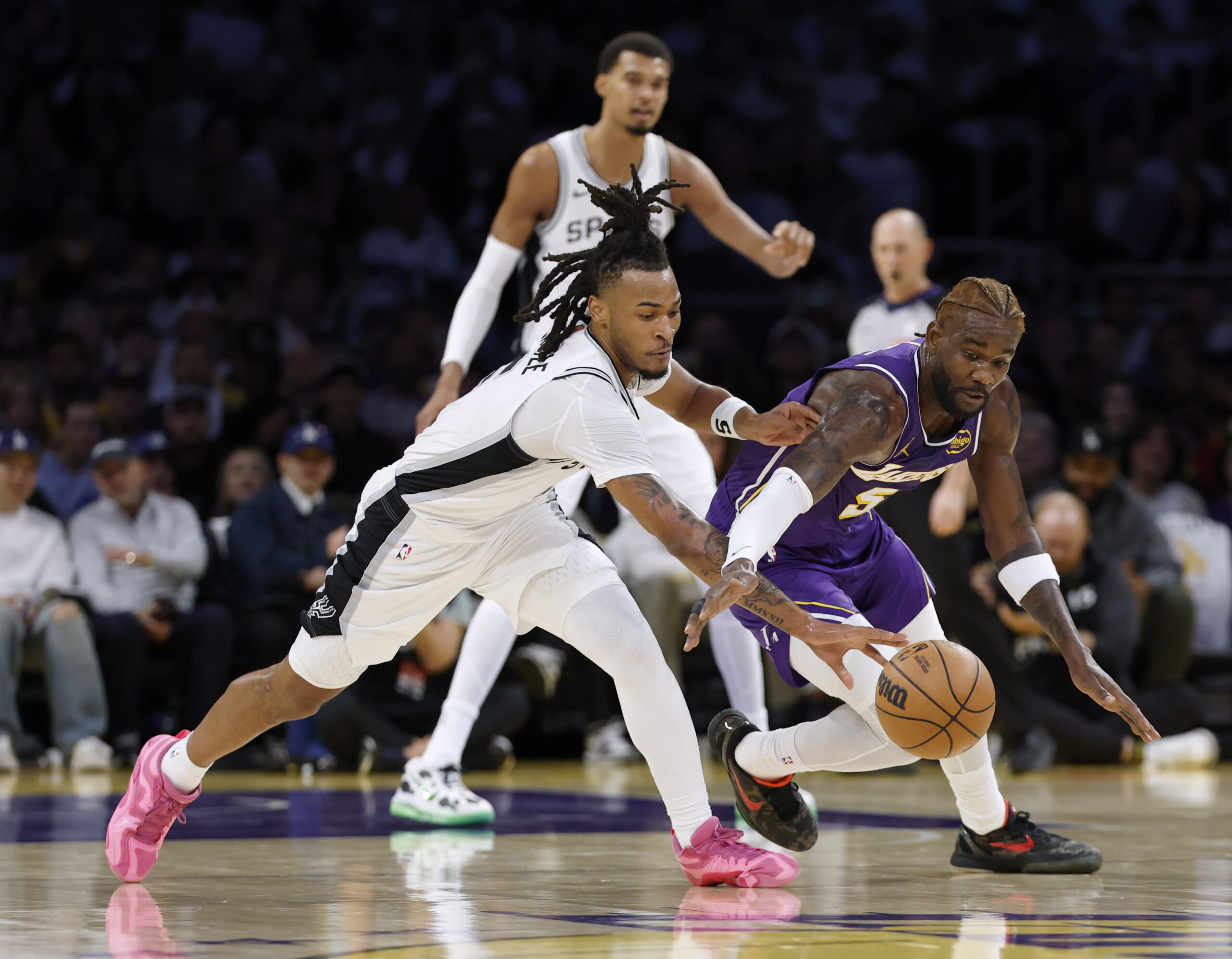 The San Antonio Spurs’ Stephon Castle, left, knocks the ball...