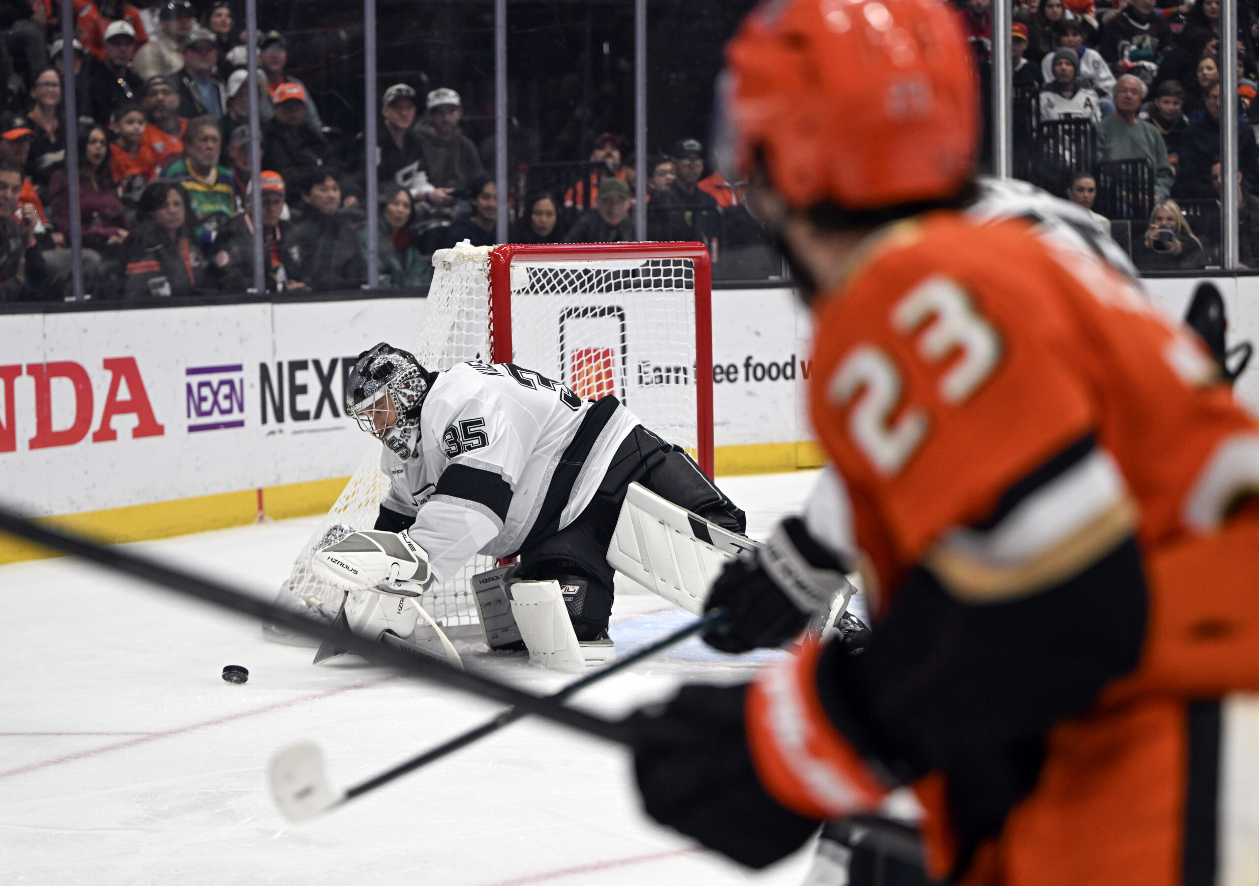 Kings goaltender Darcy Kuemper, left, dives for the puck during...