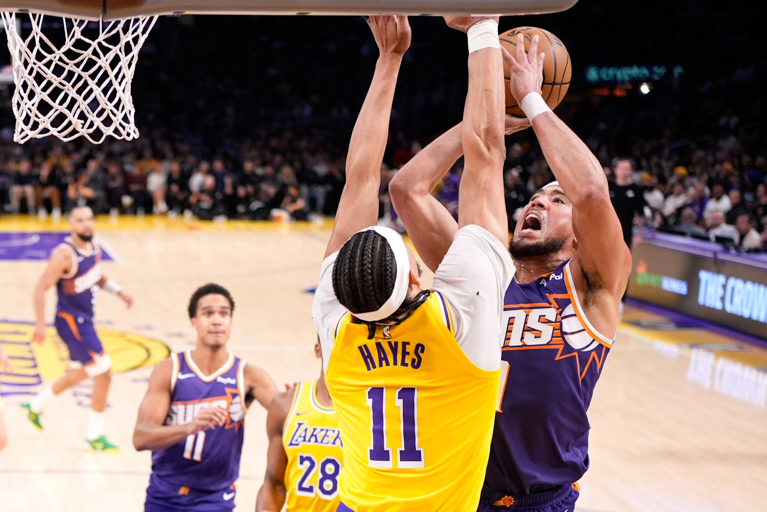 Phoenix Suns guard Devin Booker, right, shoots as Lakers center...