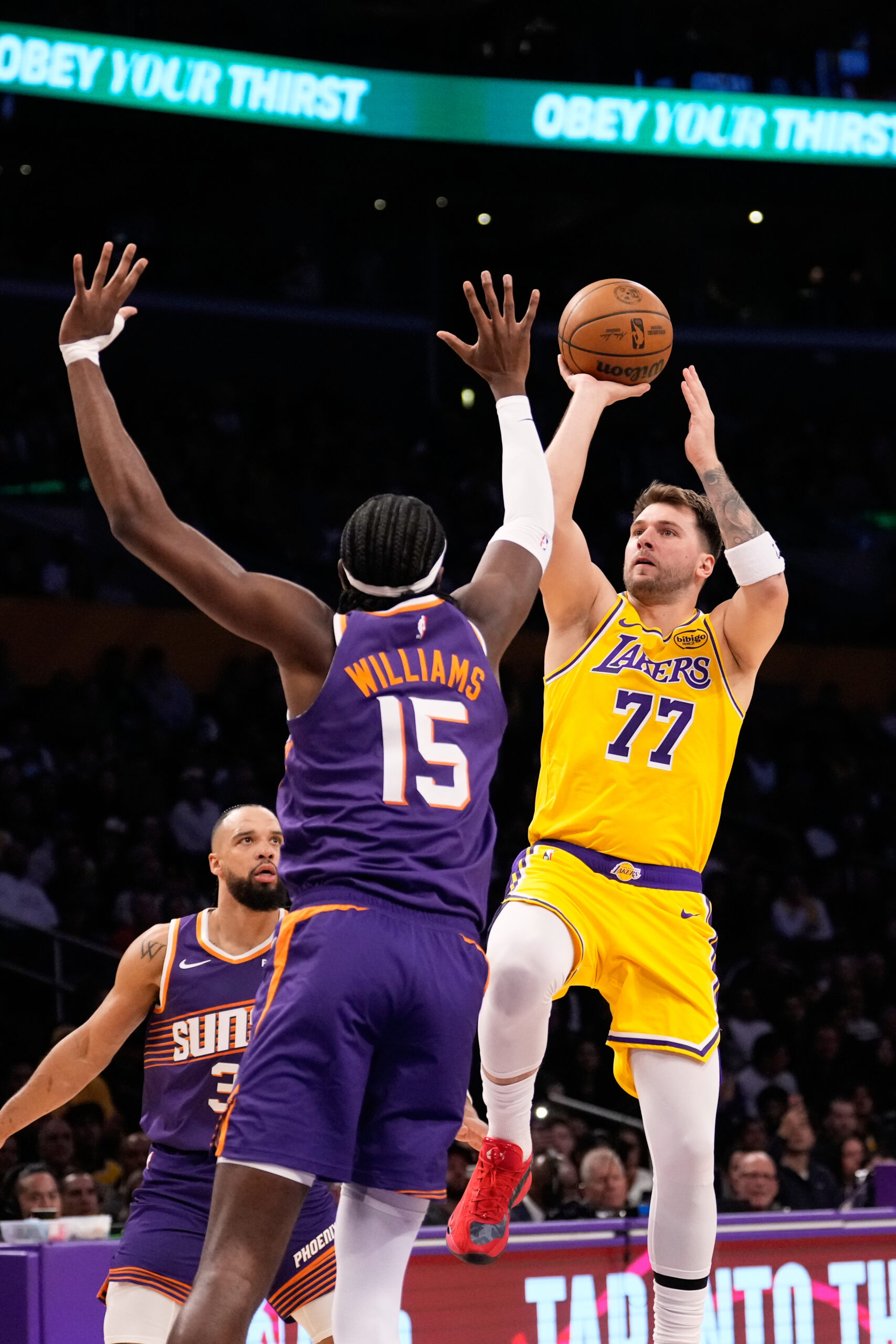 Lakers guard Luka Doncic, right, shoots as Phoenix Suns center...