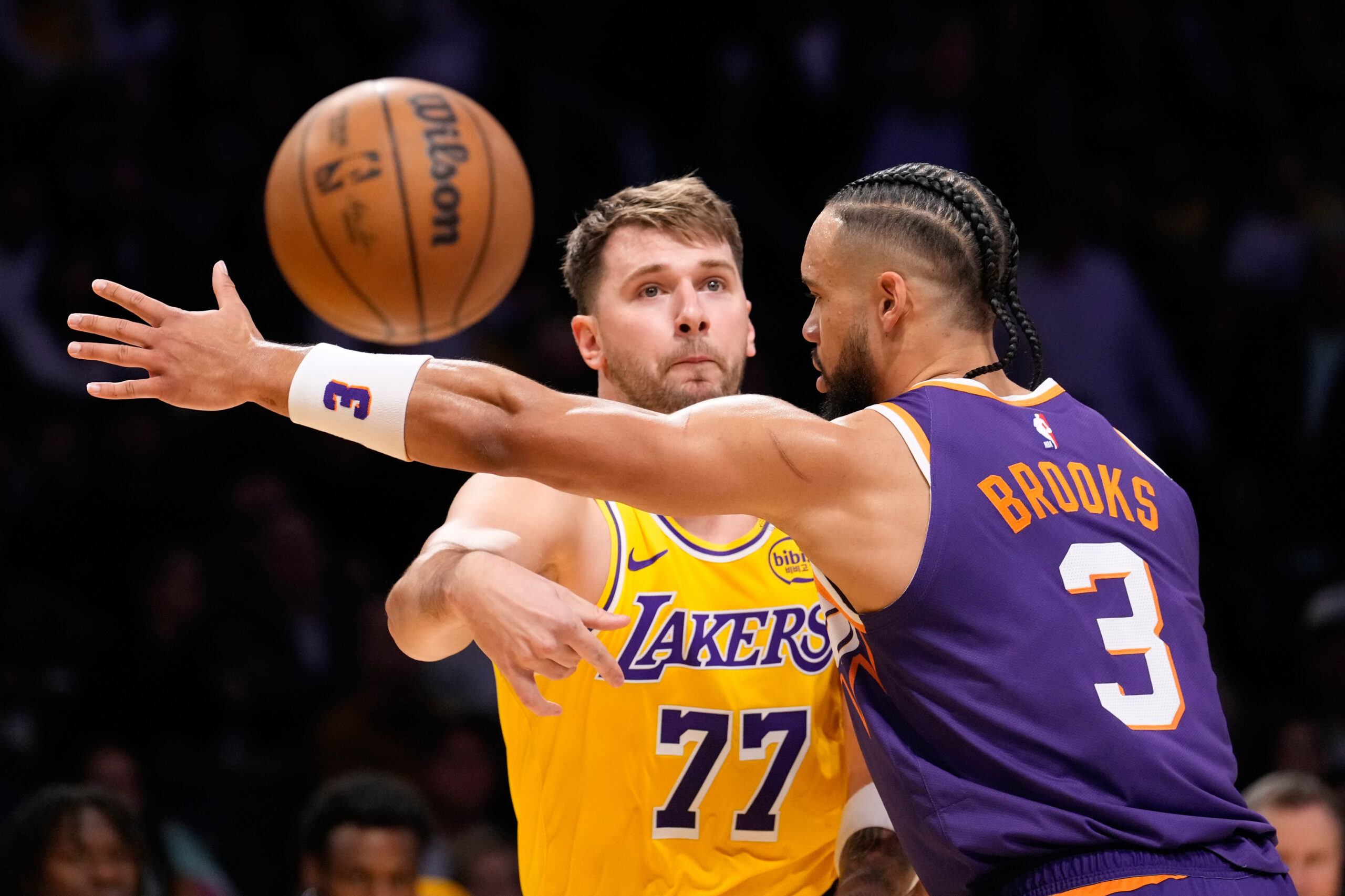 Lakers guard Luka Doncic, left, passes the ball while under...