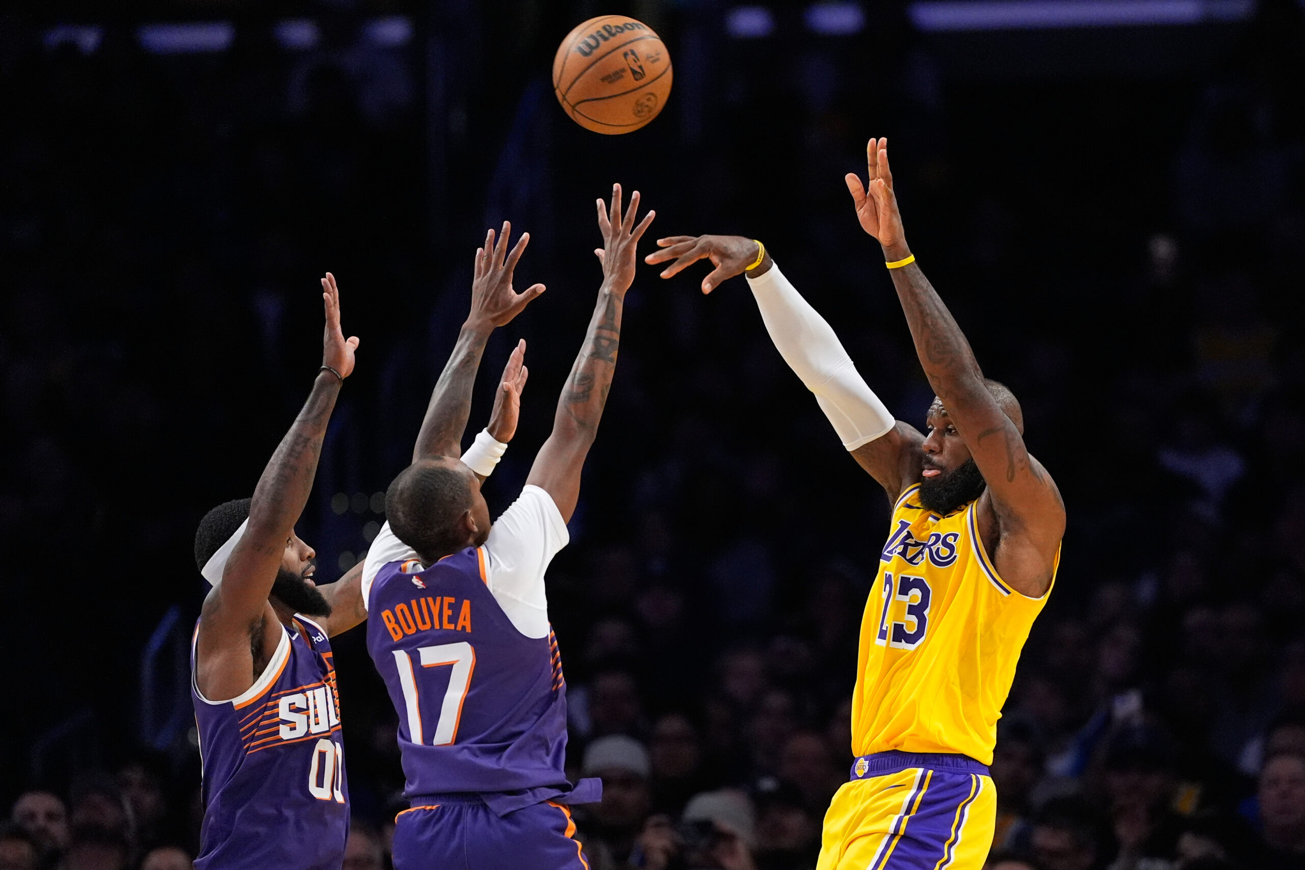Lakers forward LeBron James, right, passes the ball while under...
