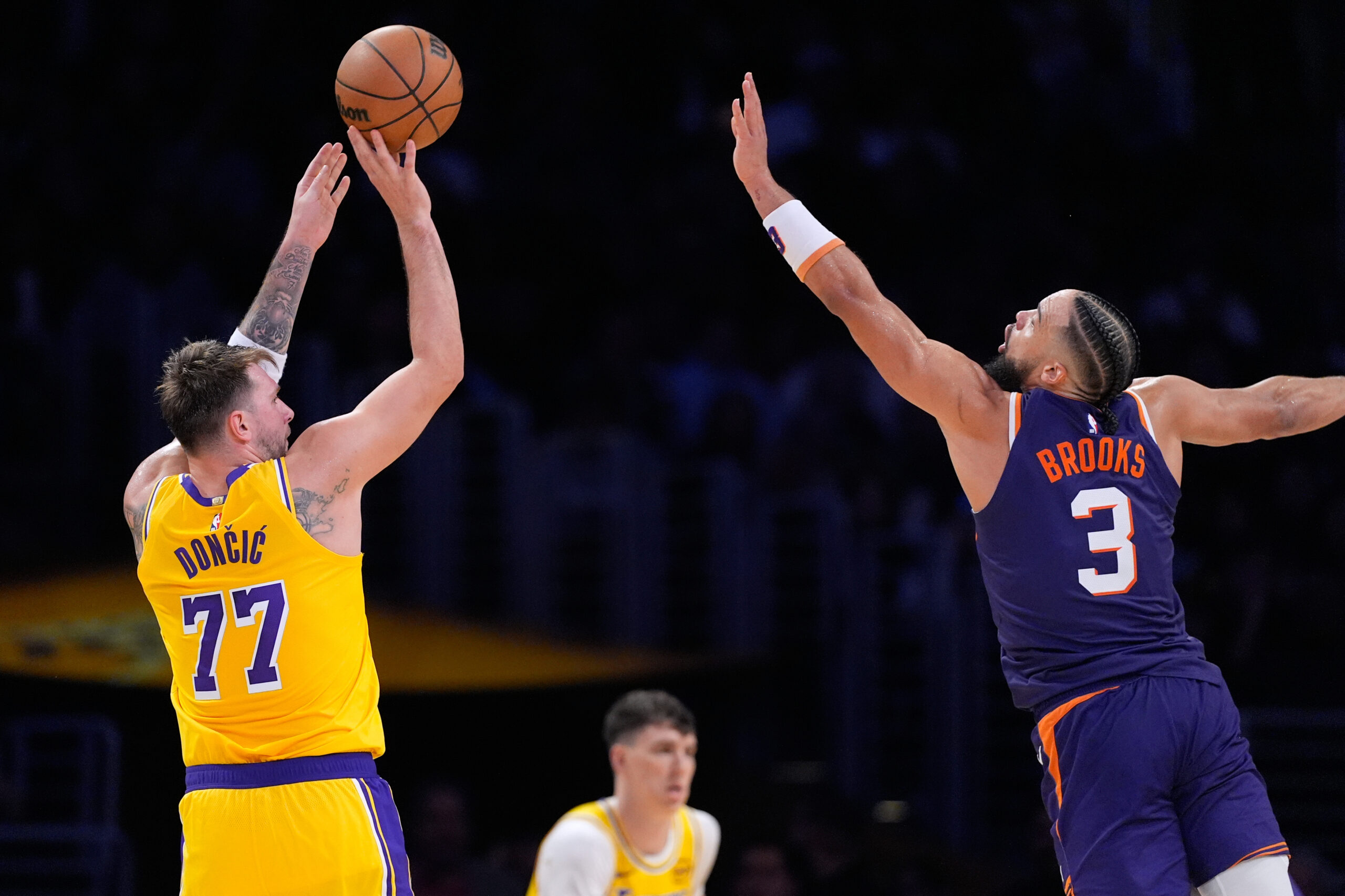 Lakers guard Luka Doncic, left, shoots as Phoenix Suns forward...