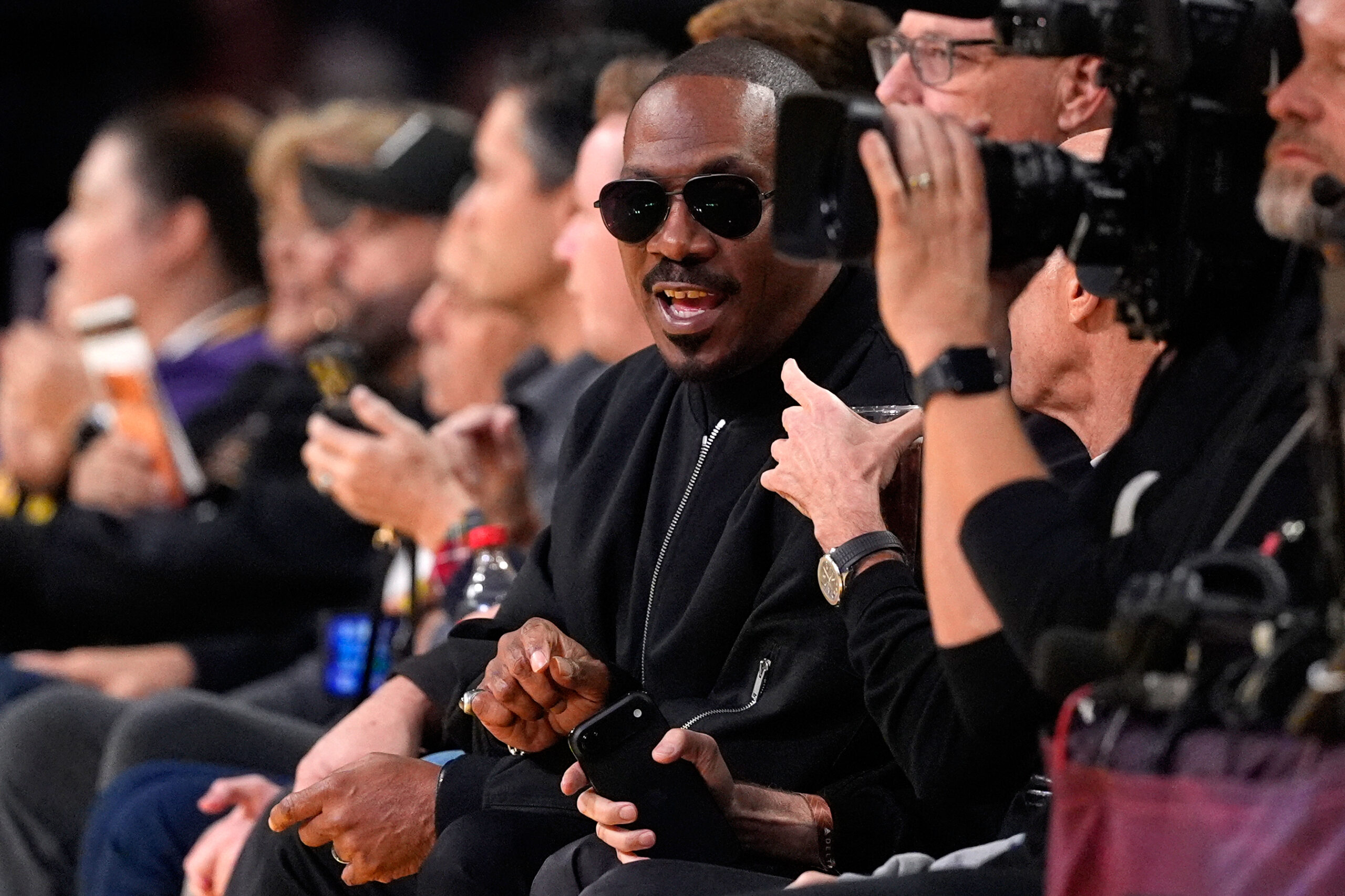 Actor Eddie Murphy watches from a courtside seat during the...