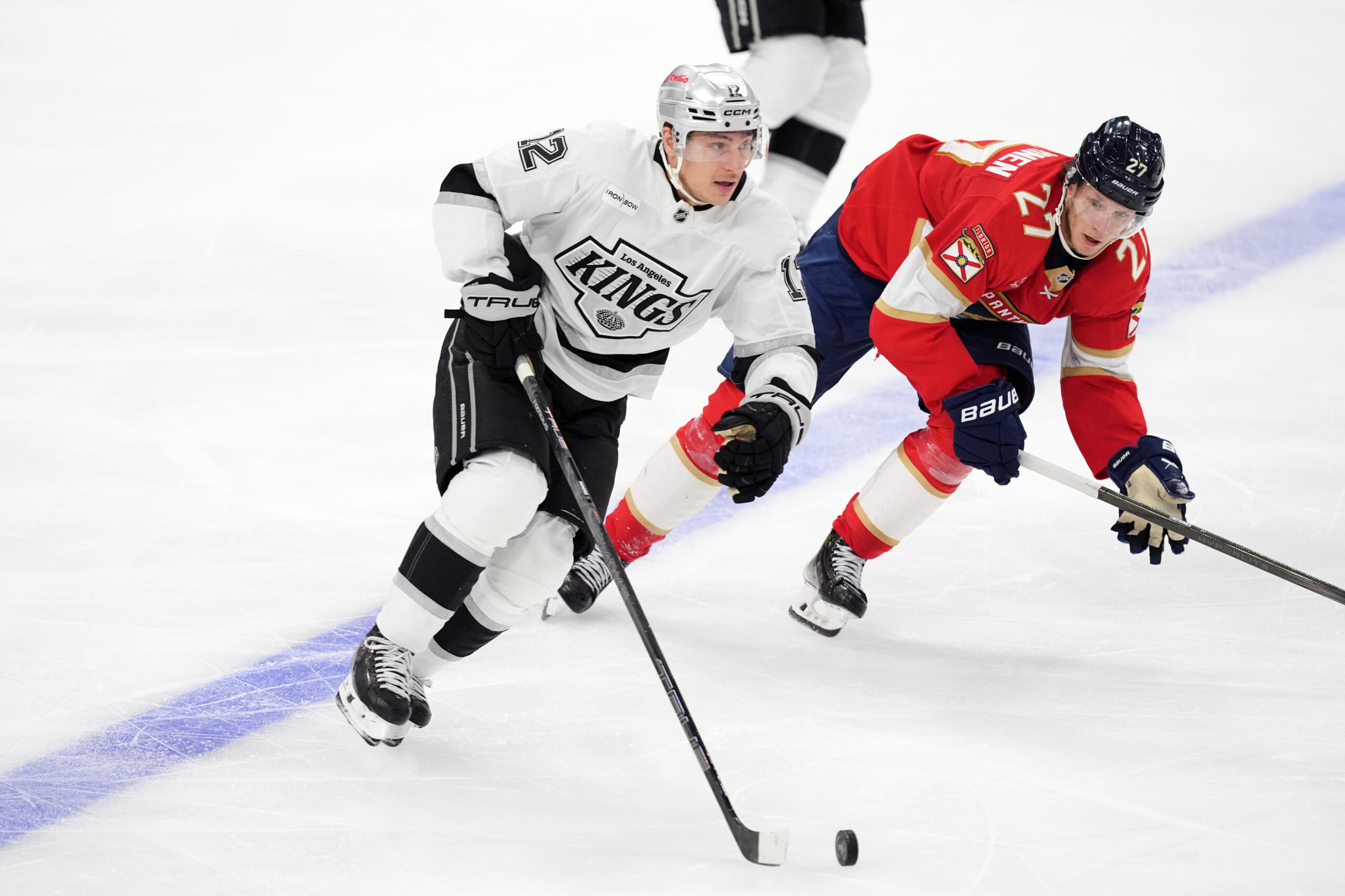 Kings left wing Trevor Moore, left, handles the puck as...