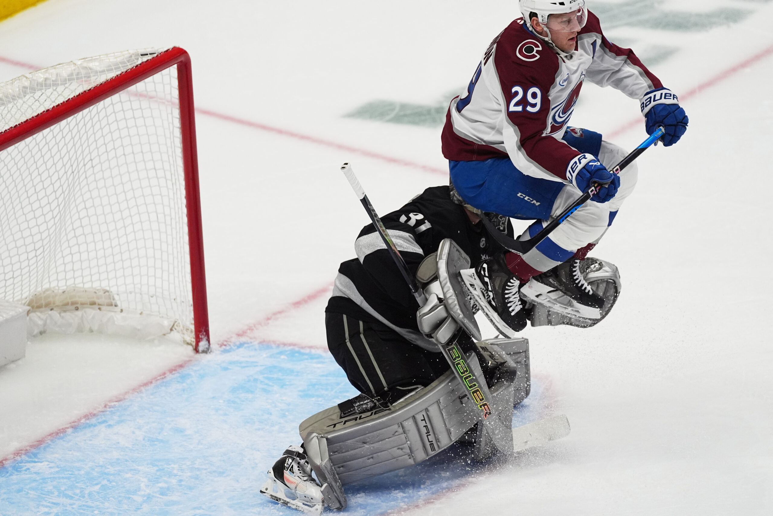 Colorado Avalanche center Nathan MacKinnon, front, jumps to block Kings...