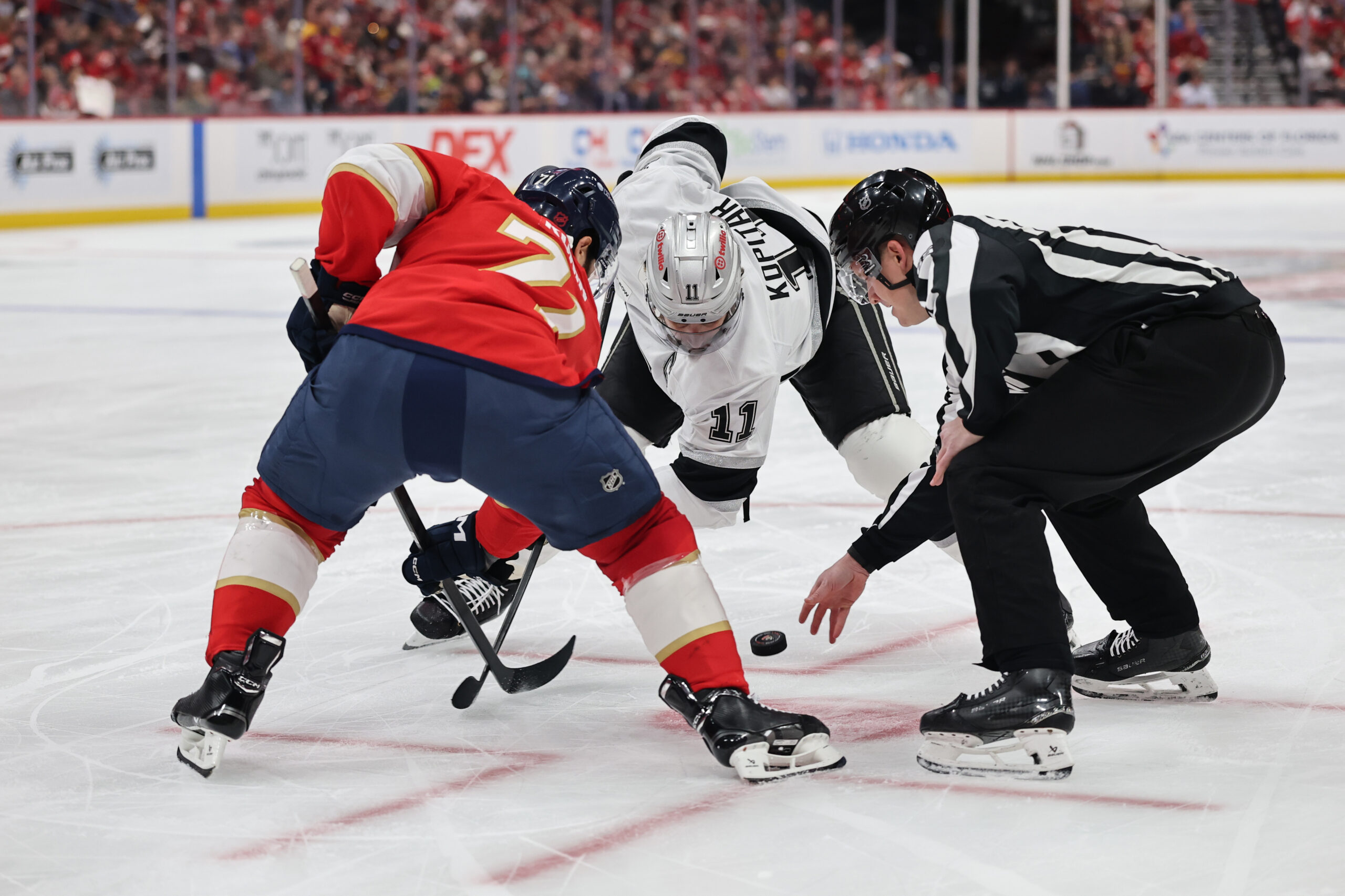 The Florida Panthers’ Luke Kunin (71) faces off against Kings...