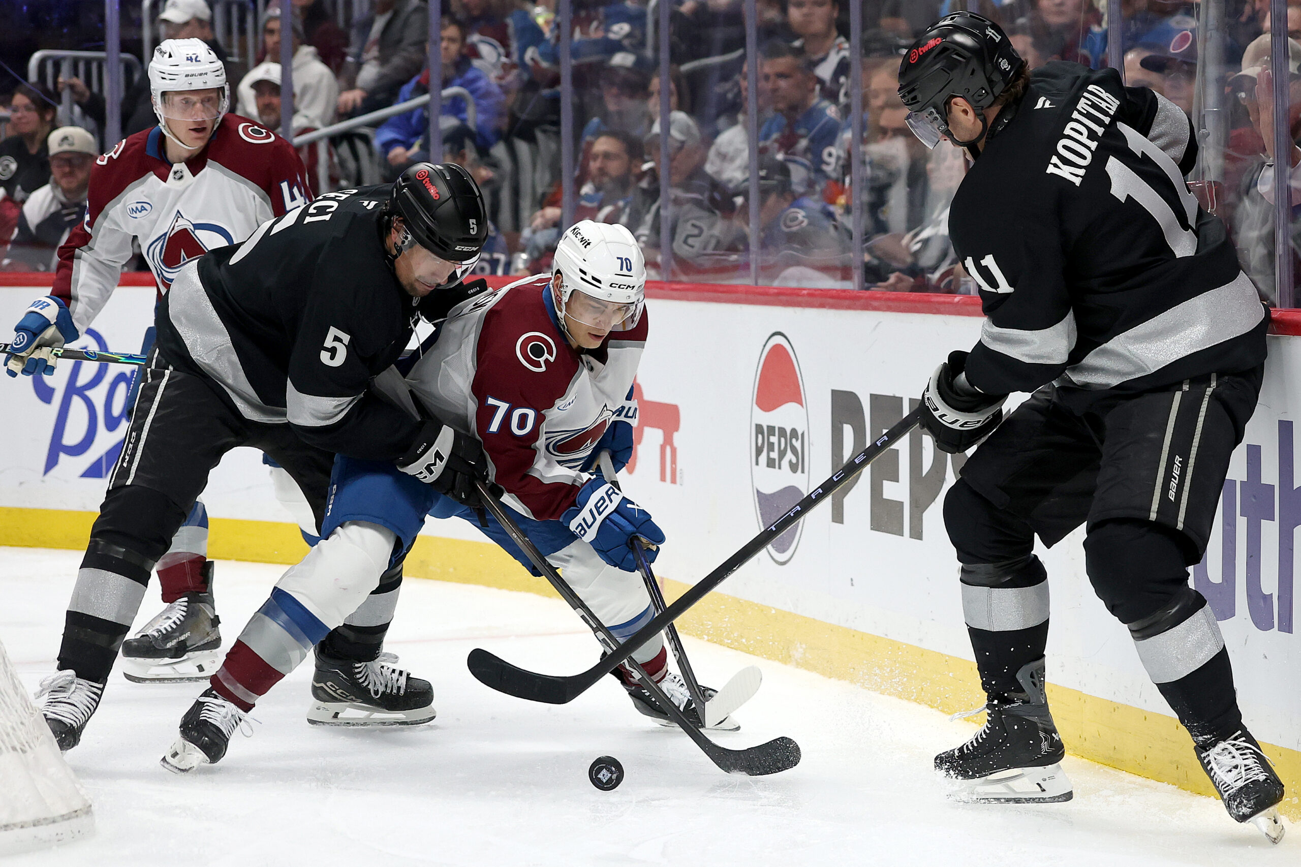 The Colorado Avalanche’s Sam Malinski, center, battles for the puck...