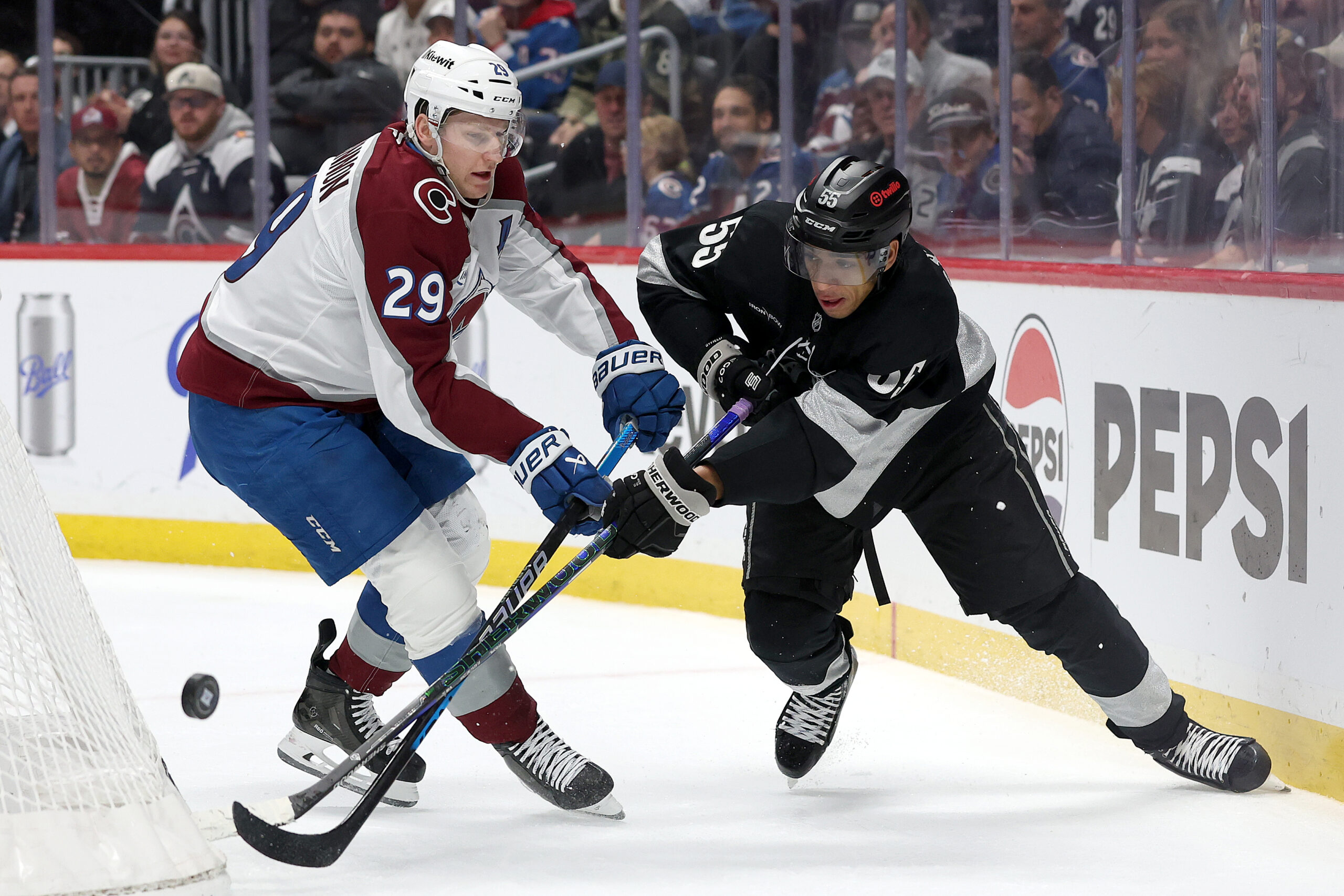 The Colorado Avalanche’s Nathan MacKinnon, left, battles for the puck...