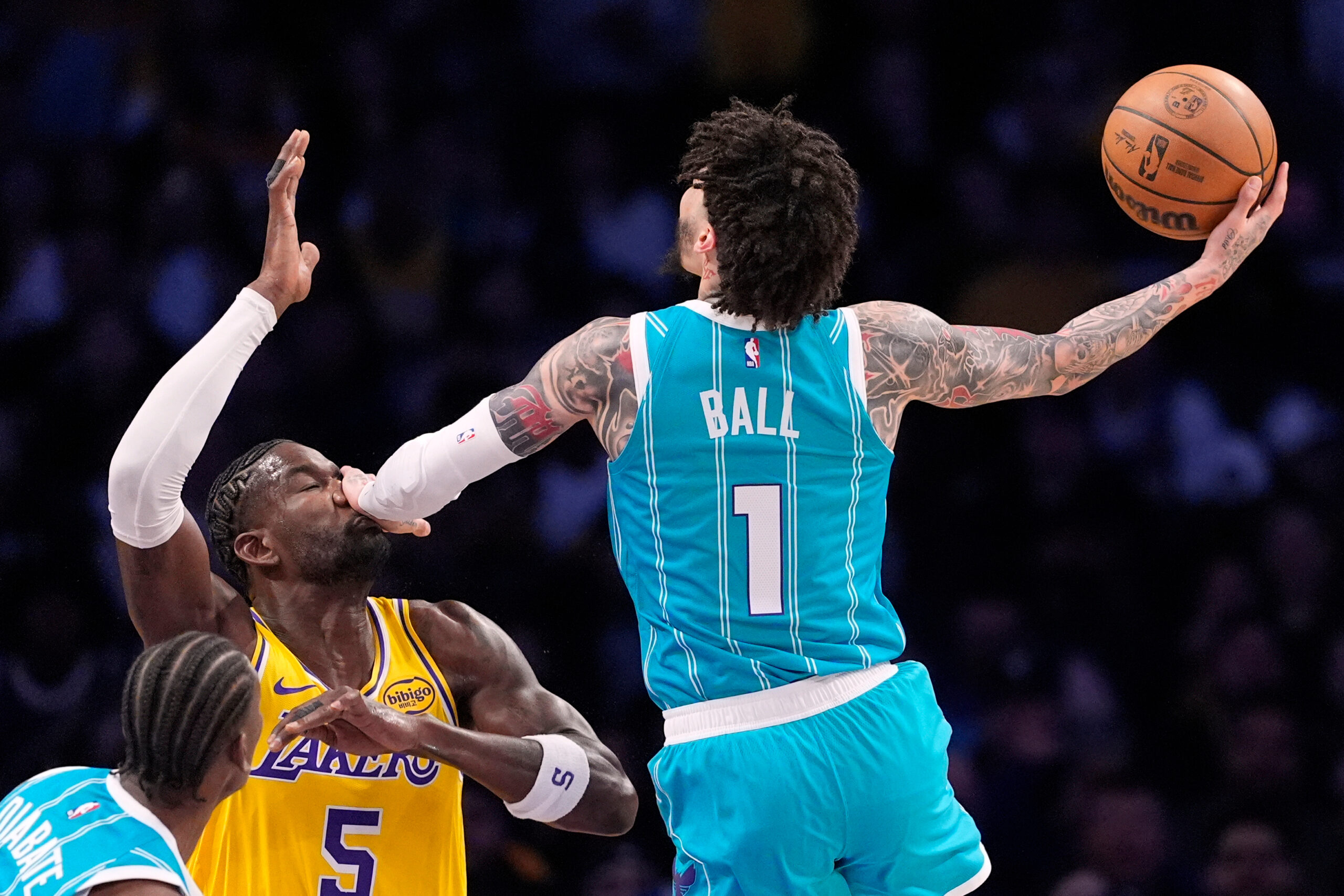 Charlotte Hornets guard LaMelo Ball, right, hits Lakers center Deandre...