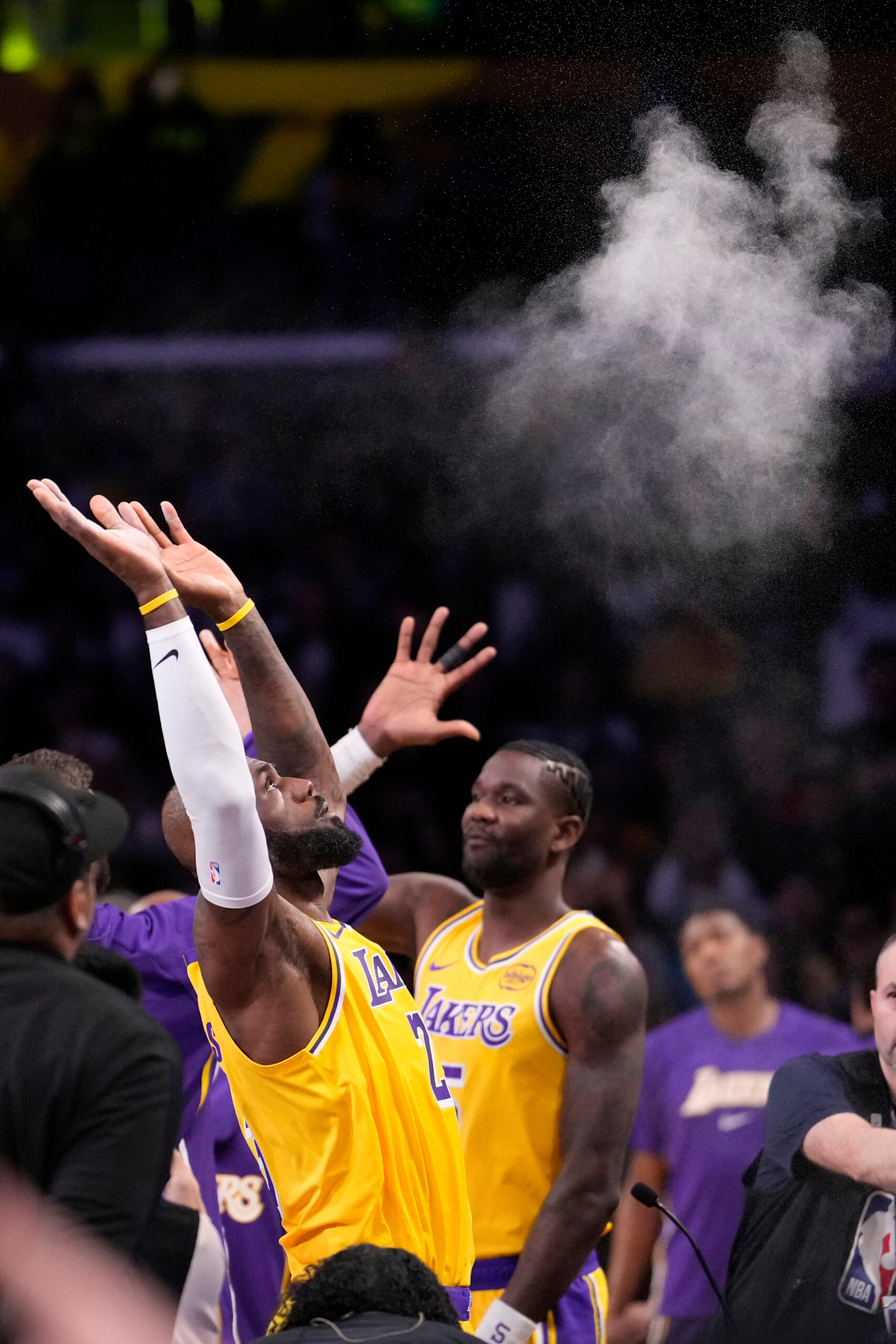 Lakers forward LeBron James tosses powder in the air before...