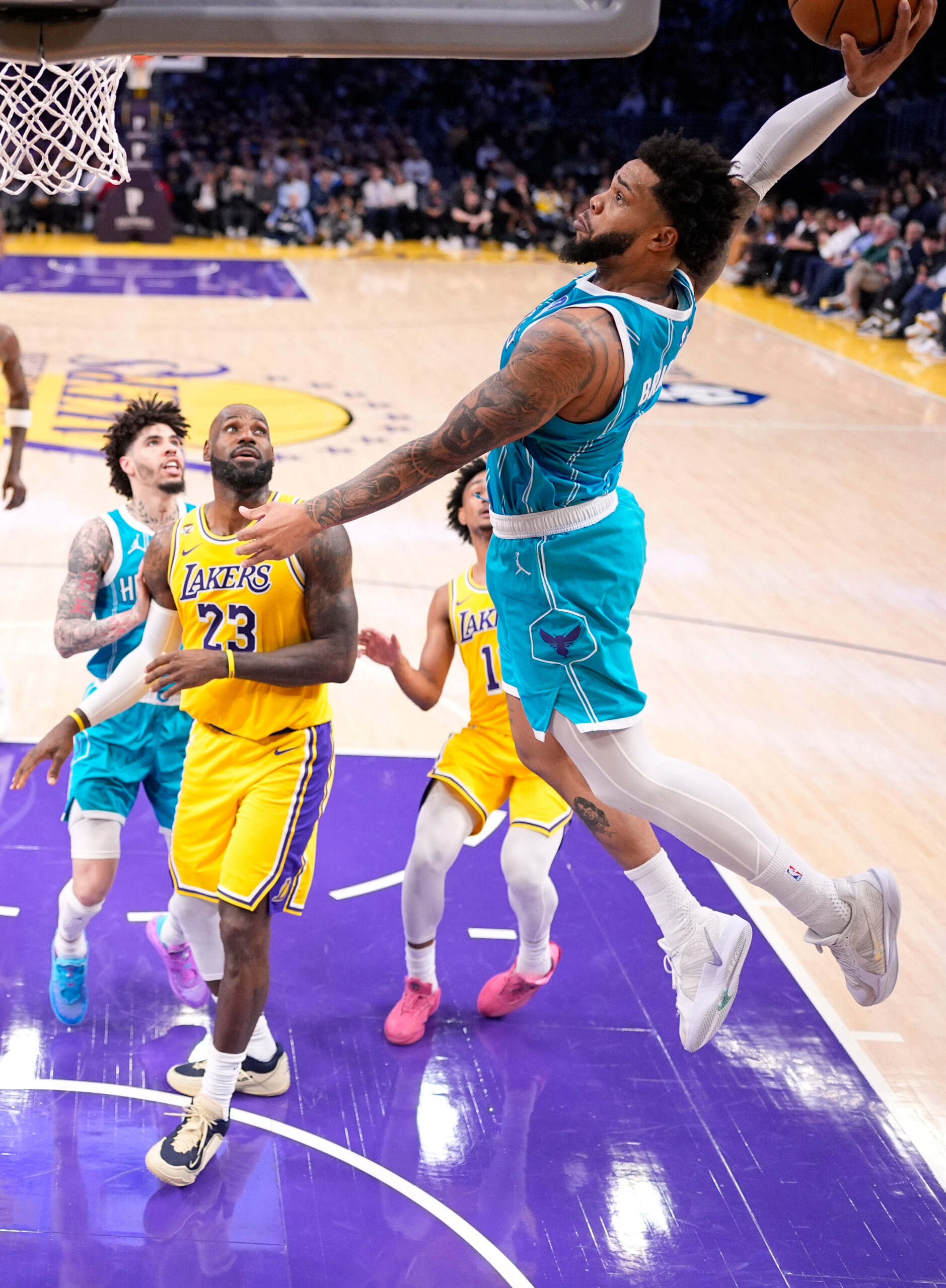 Charlotte Hornets forward Miles Bridges, right, dunks as Lakers forward...