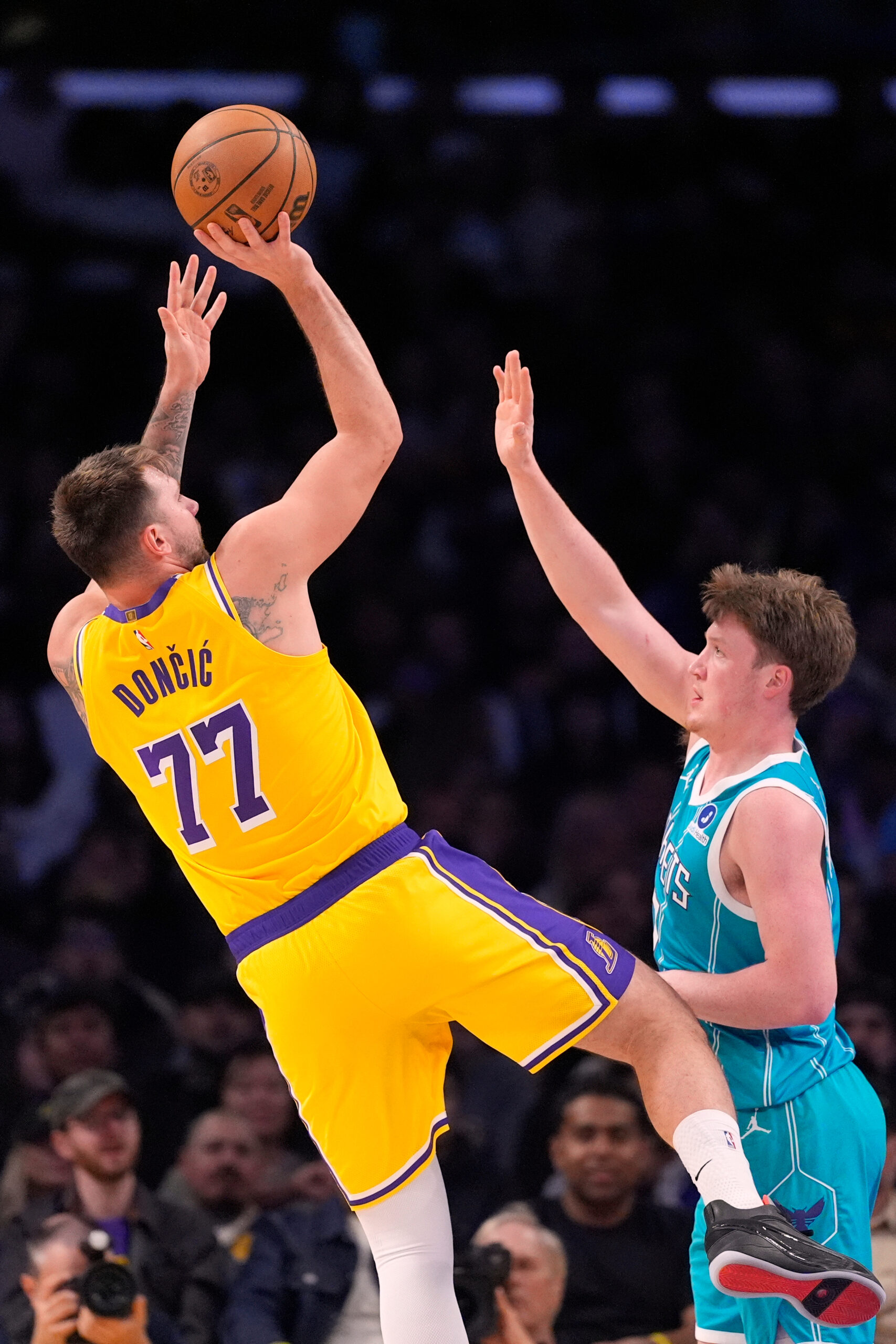 Lakers guard Luka Doncic, left, shoots as Charlotte Hornets guard...