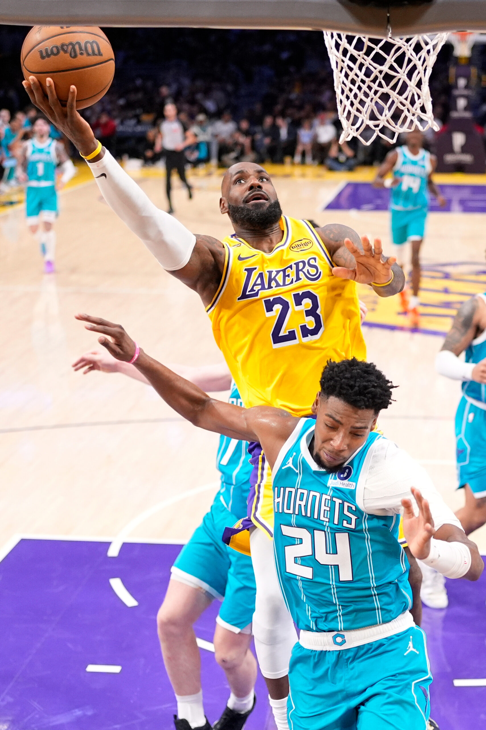 Lakers forward LeBron James, top, shoots as Charlotte Hornets forward...