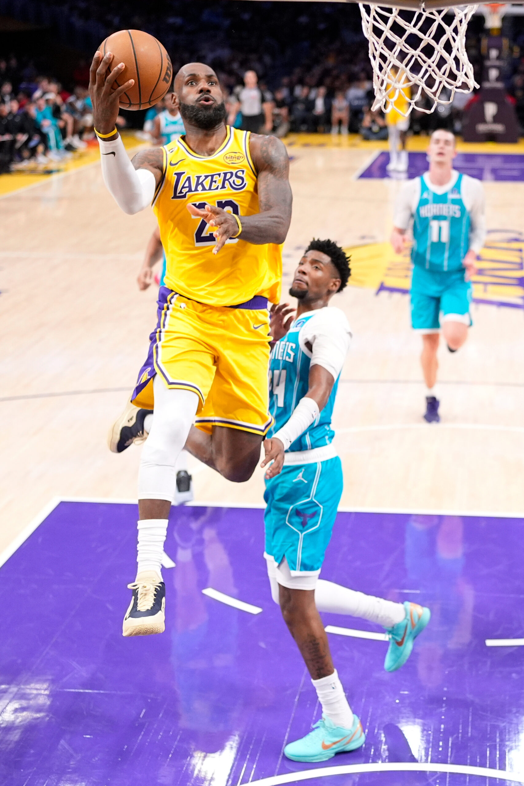 Lakers forward LeBron James, top, shoots as Charlotte Hornets forward...