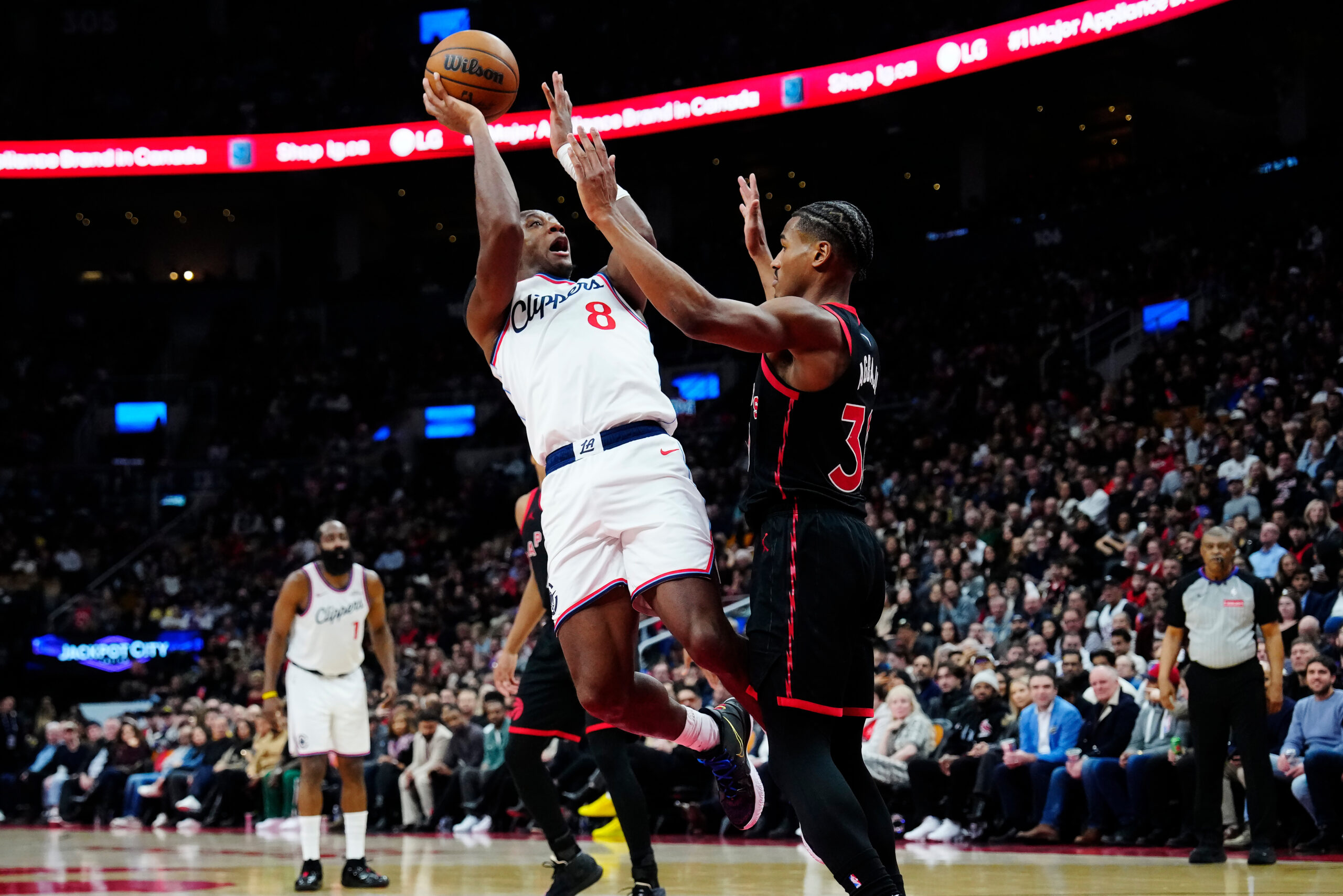 Clippers guard Kris Dunn, left, shoots as the Toronto Raptors’...