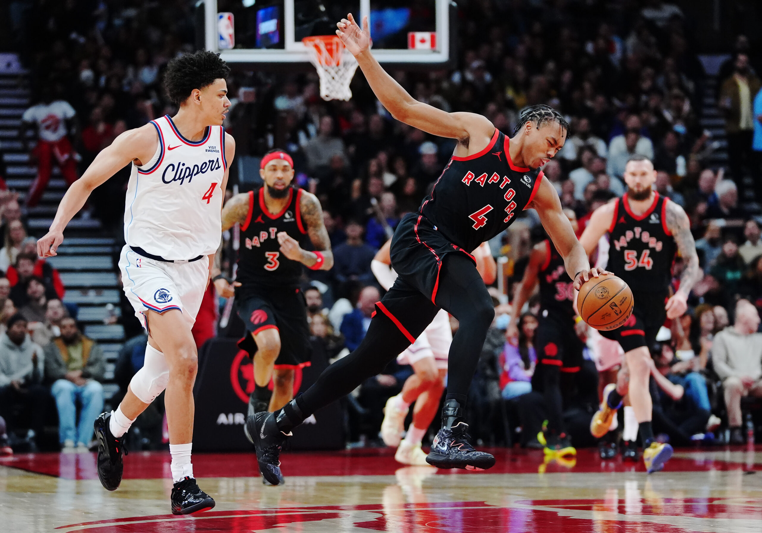 The Toronto Raptors’ Scottie Barnes, right, stumbles while chasing the...