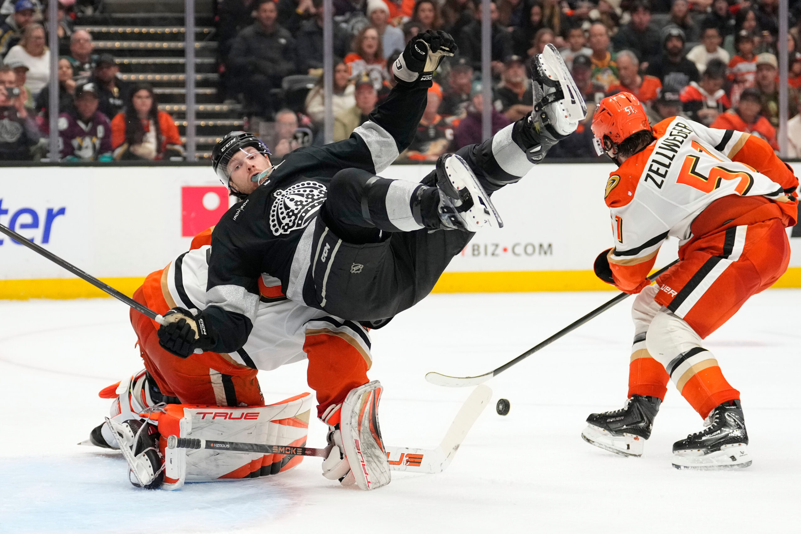 Kings left wing Warren Foegele, center, falls over Ducks goaltender...