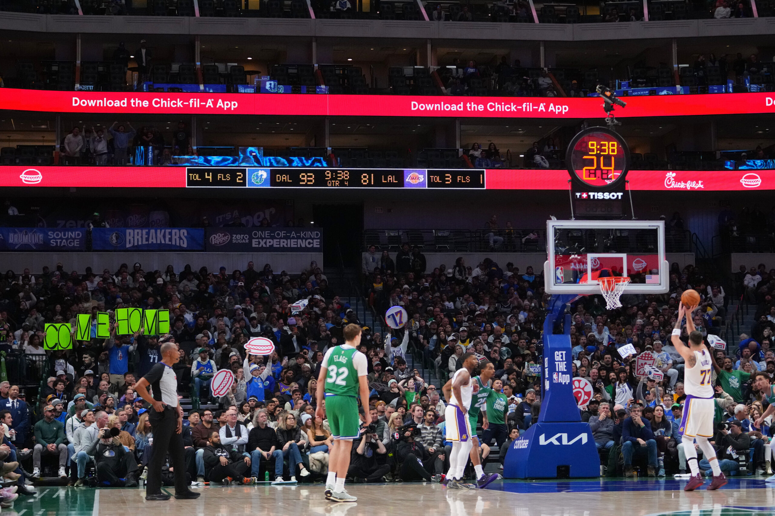Spectators, left, hold signs with a message for Lakers guard...