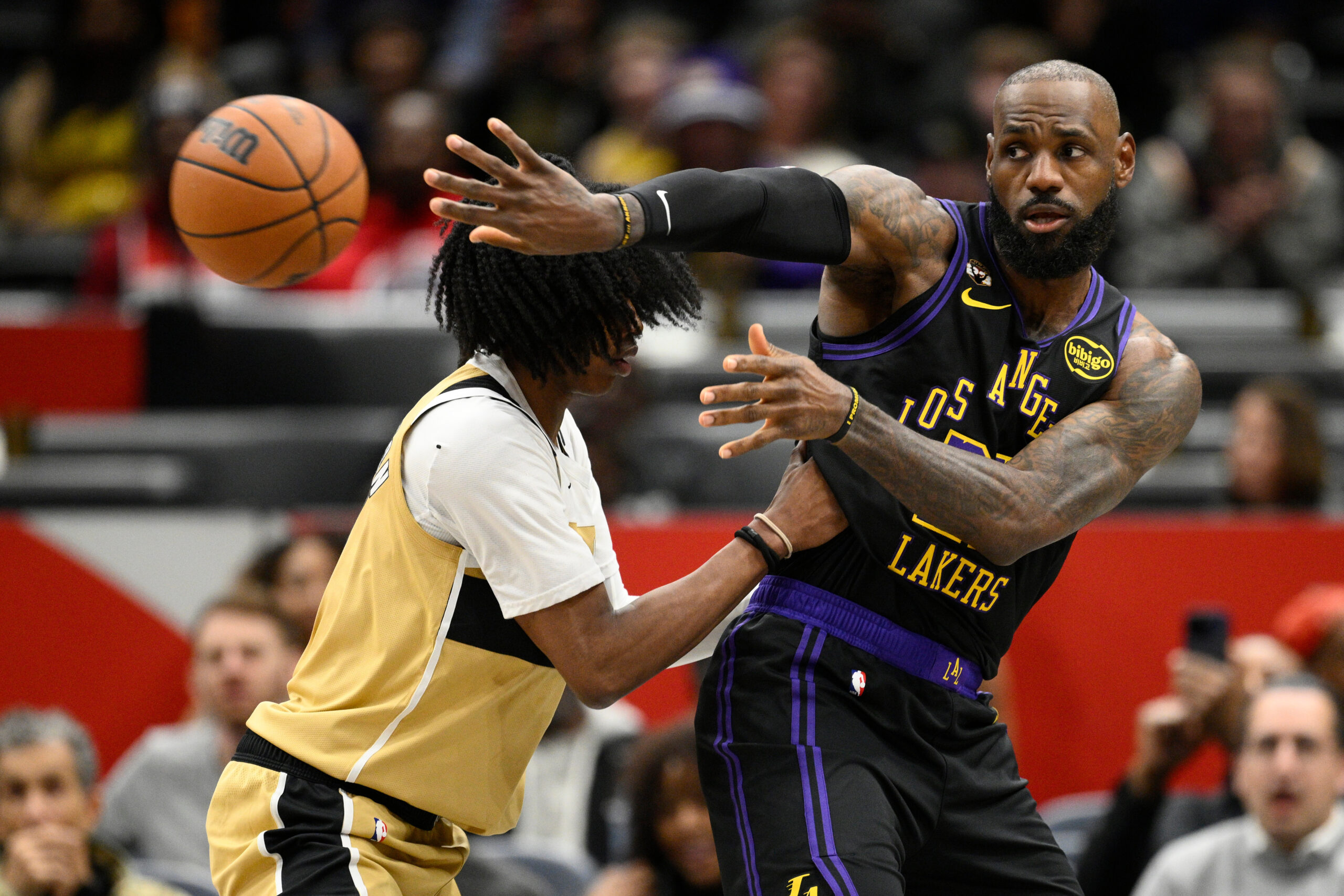 Lakers star LeBron James, right, passes the ball as Washington...