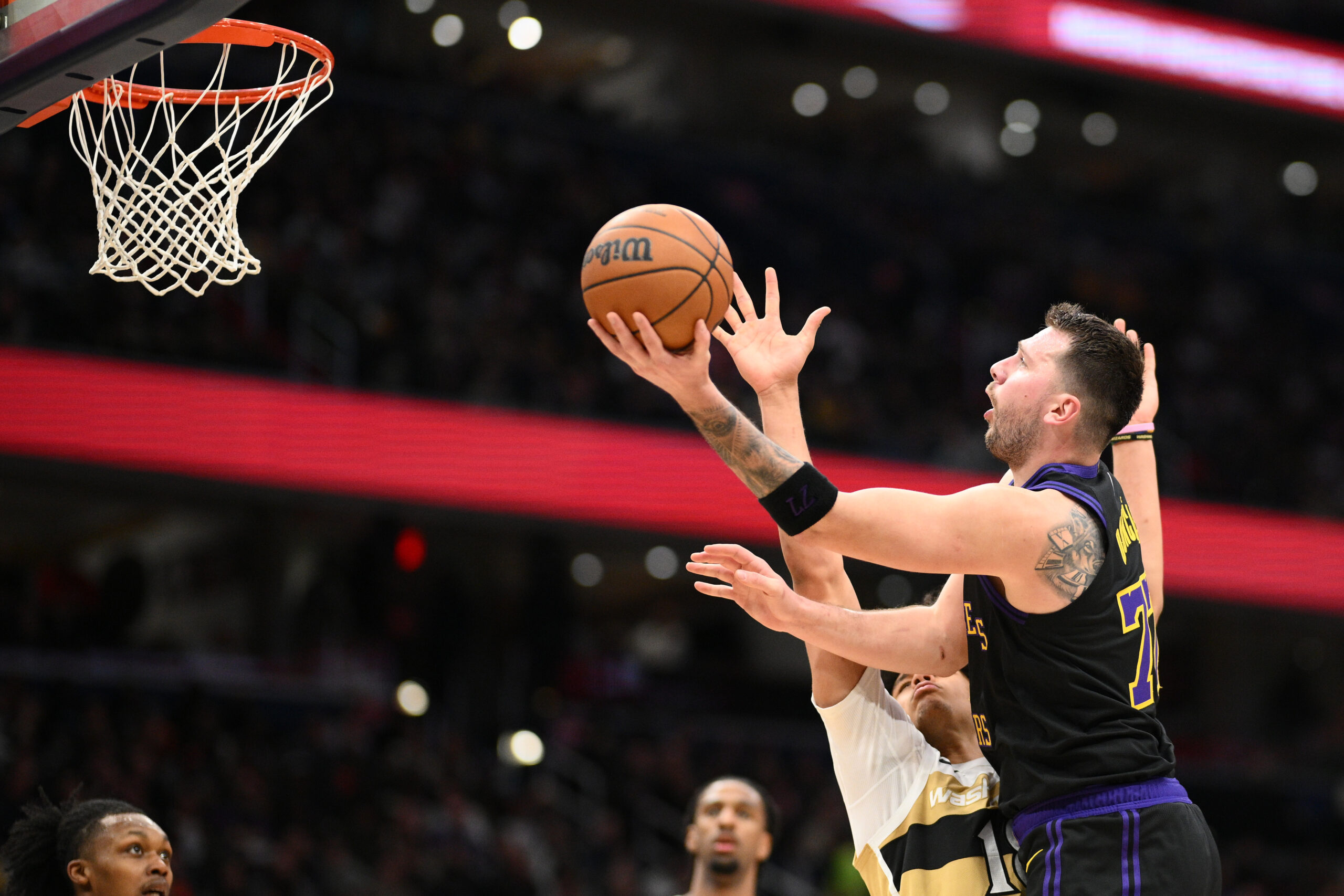 Lakers star Luka Doncic, right, goes to the basket against...