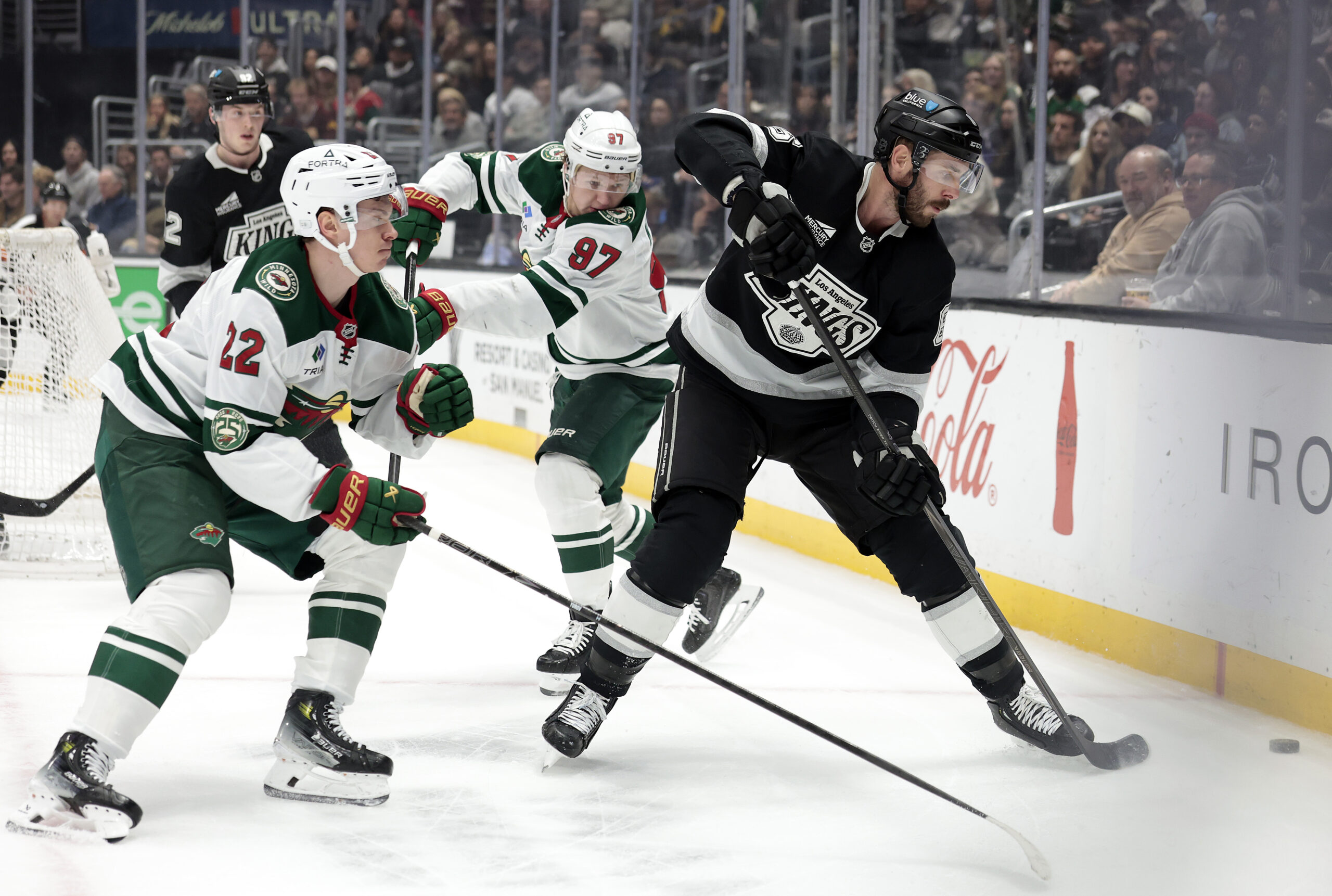 The Kings’ Joel Edmundson, right, skates with the puck as...