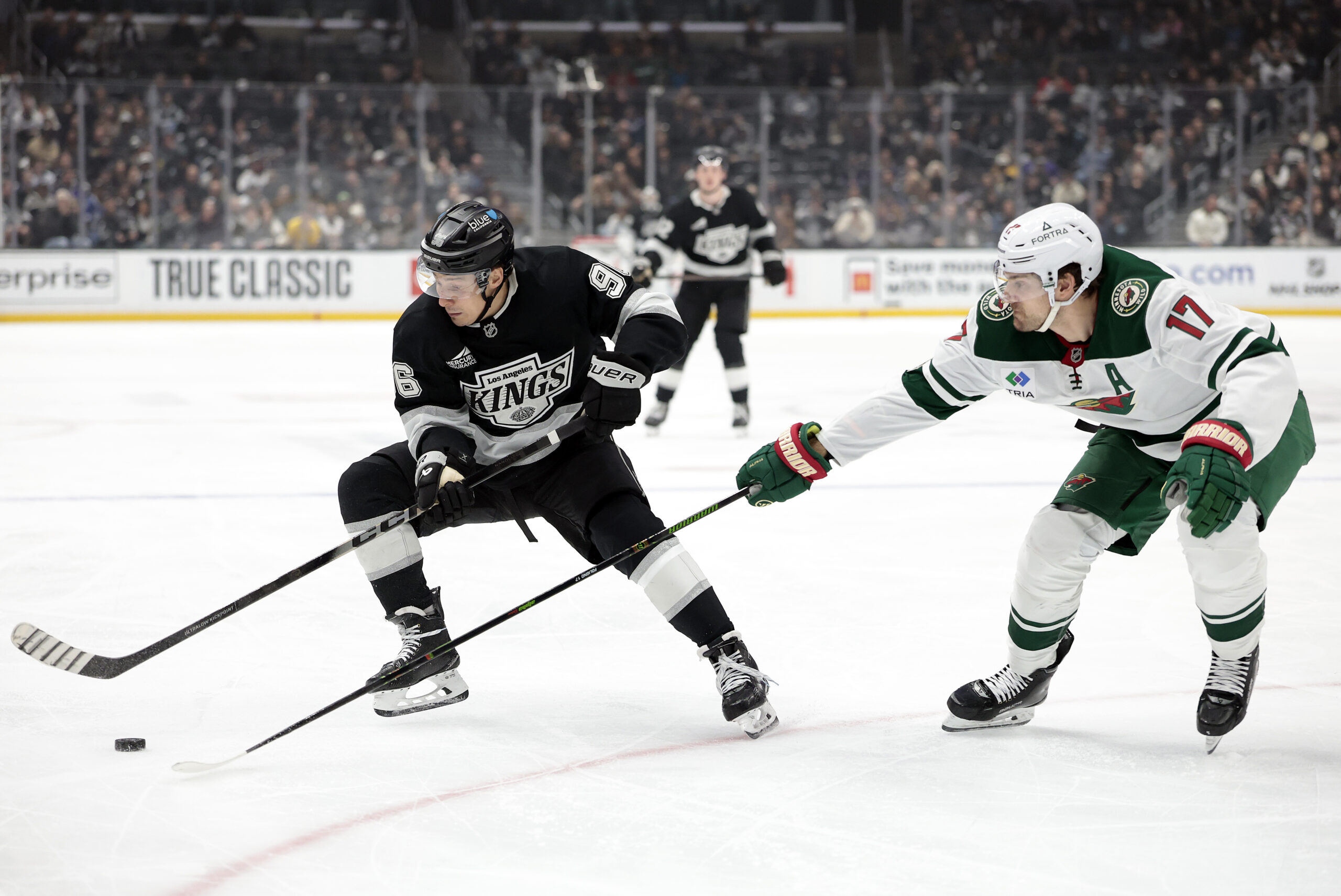 The Kings’ Andrei Kuzmenko, left, skates with the puck as...