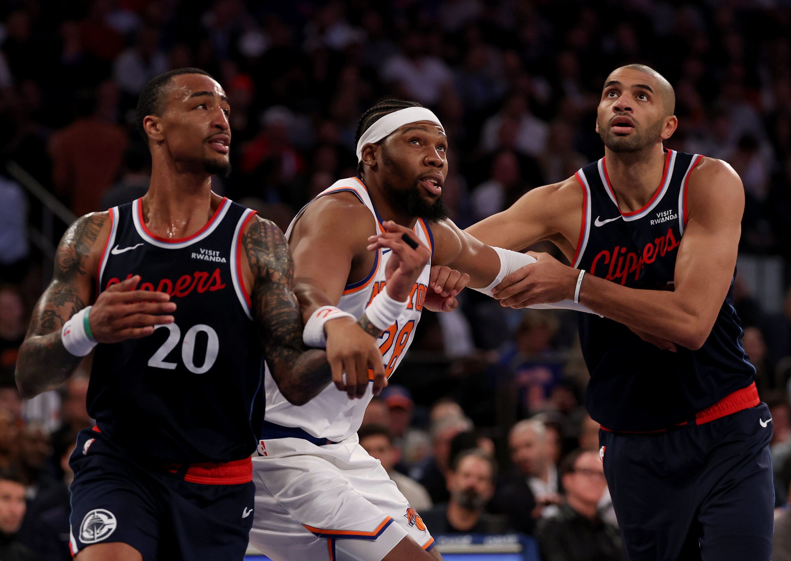 Clippers forwards John Collins, left, and Nicolas Batum, right, battle...