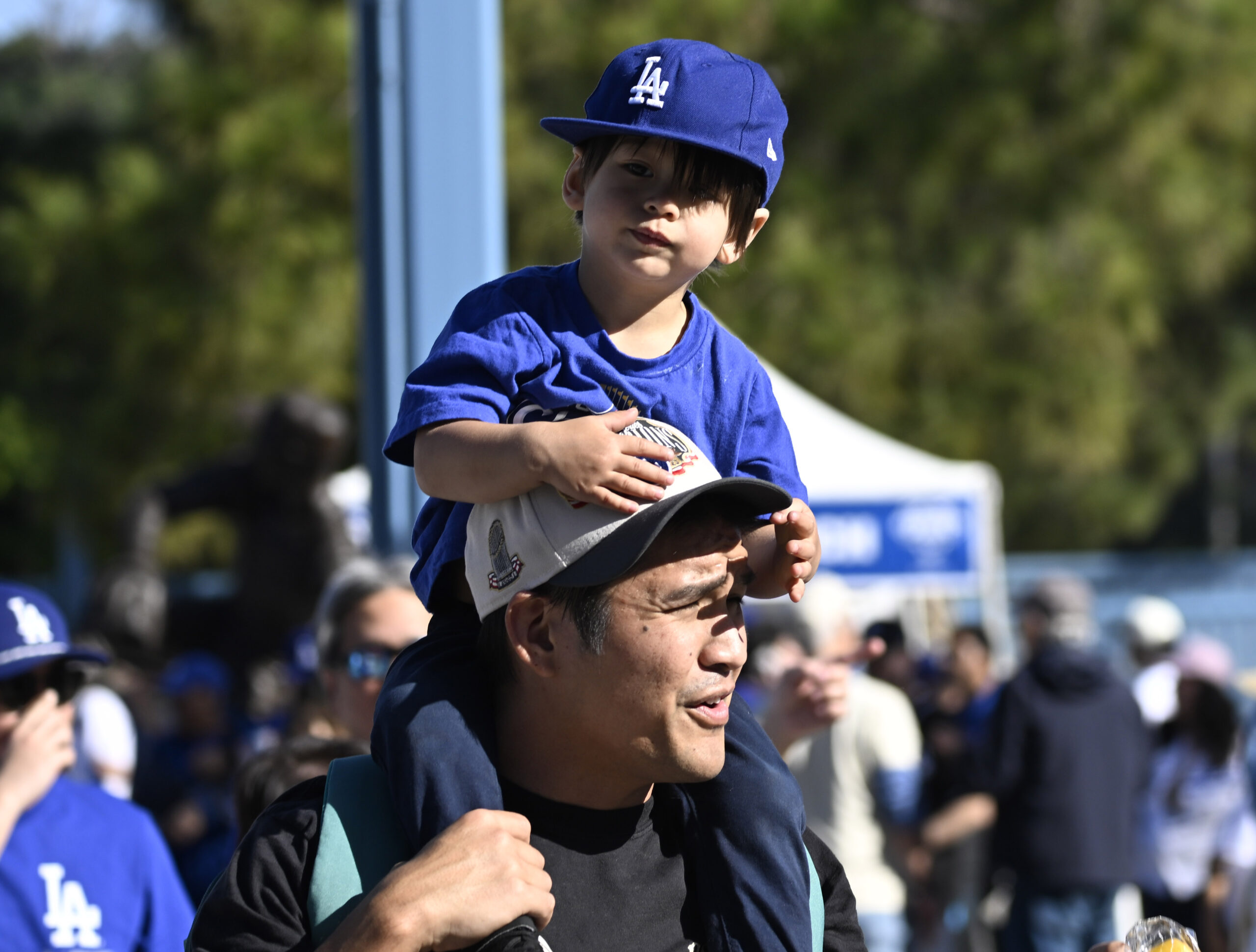 A young Dodger fan sits atop his father during the...