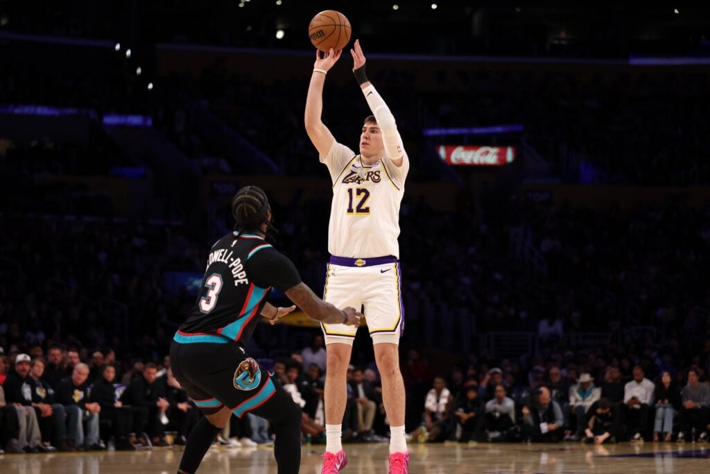 Jan 4, 2026; Los Angeles, California, USA; Los Angeles Lakers forward Jake Laravia (12) shoots the ball over Memphis Grizzlies guard Kentavious Caldwell-Pope (3) during the first half at Crypto.com Arena. Mandatory Credit: Kiyoshi Mio-Imagn Images