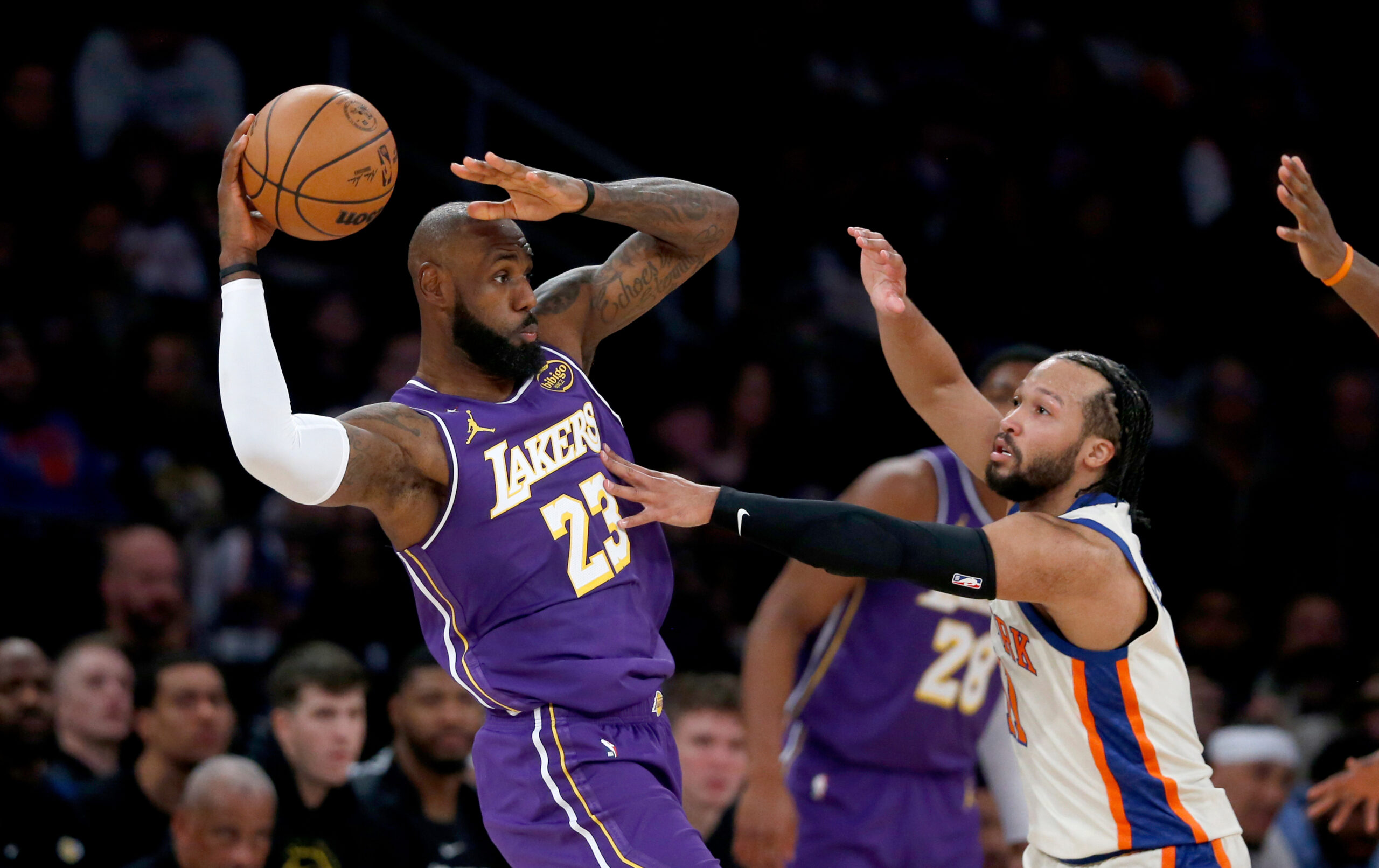Lakers forward LeBron James, left, looks to pass the ball...